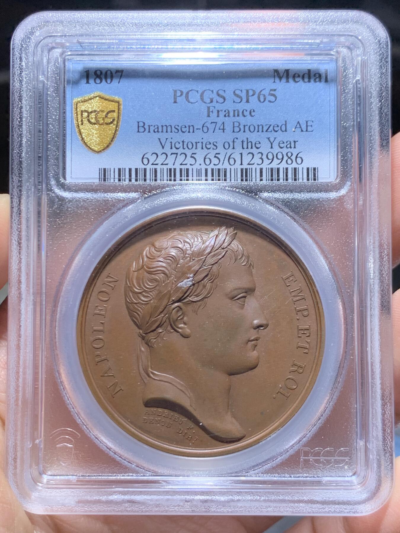 《竞宝斋》第469场 周日，周一 2场连拍 （全场包邮）欢迎送拍 PCGS SP65 冠军分！法国1807年拿破仑一世年度胜利原铸铜章 巴黎造币厂 巧克力包浆 帝国之鹰展翅爪子锋利 紧紧攥住矗立于N记雷电权杖之上 目光锐利如炬 羽翼丰满 丝缕清晰细节感人 作为拿皇的拟人化象征 接受上空胜利女神飞舞空中送来月桂花环为其加冕 作为年度总结庆祝过去的一年中军队获取的胜利 稀少珍贵品种 加厚盒