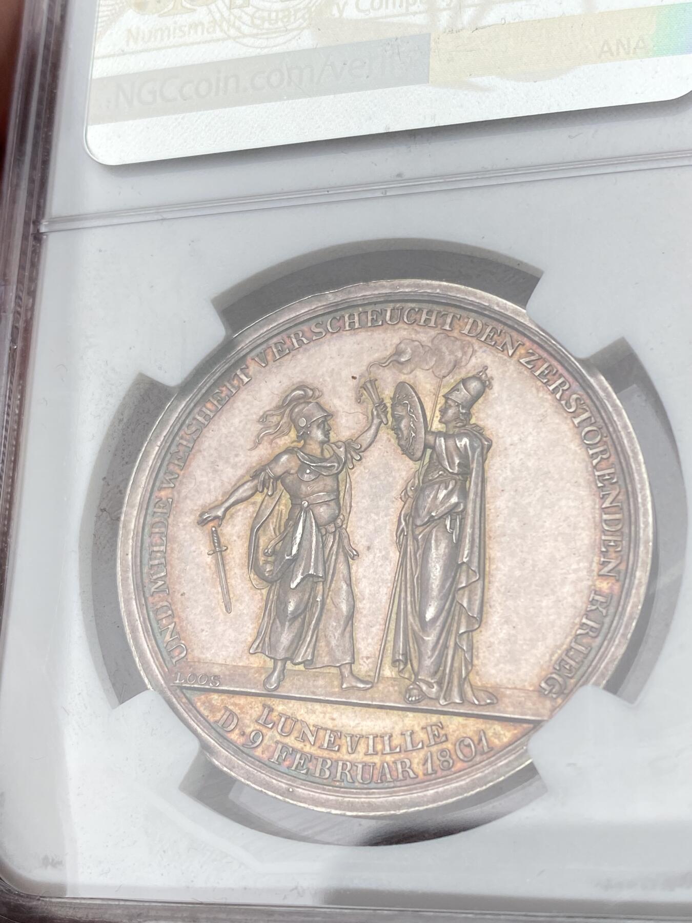 万国钱币拍卖第062期 NGC MS63 1801年德国吕内维尔和平纪念银章 罕见品种 和平女神站在云朵前的地球之上 背面密涅瓦女神向贝洛娜女神伸出埃癸斯盾 贝洛娜女神随即放下了手中剑 彩虹色极美均匀包浆高浮雕收藏品质