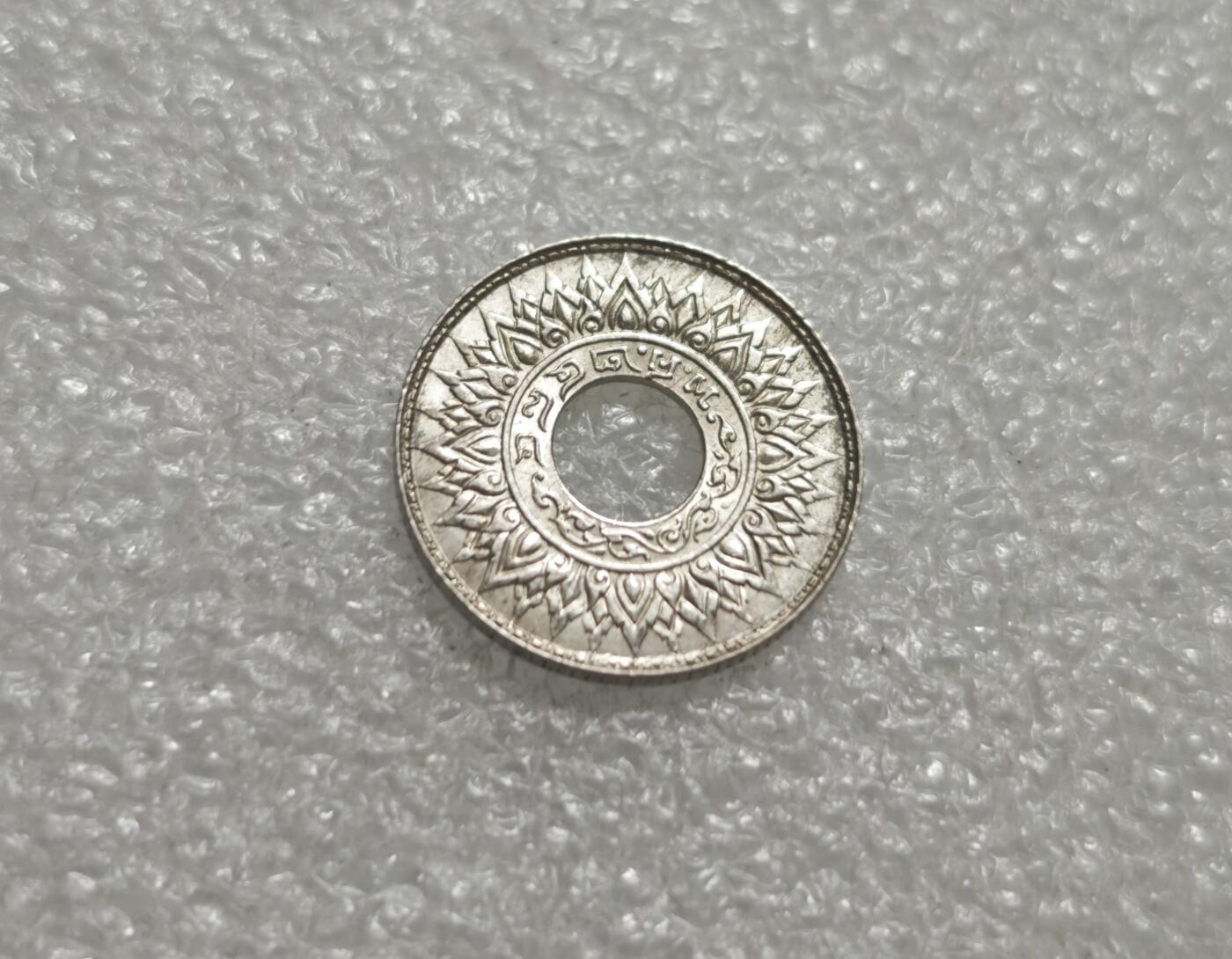 瓶子🏺第232期拍卖会  泰国1941年10萨当（Satang）圆孔银币  正面 中心为圆孔，周围环绕泰式卷草纹与尖顶佛塔纹，是暹罗传统艺术的典型符号。 泰文铭文： ๑๐ สตางค์ （10 Satang），下方为 ราชอาณาจักรไทย （泰王国） 背面 中心为圆孔，外圈是莲花瓣/火焰纹（象征佛教与王室），内圈为泰文纪年与造币厂标记（ ๒๔๘๔  即佛历2484年，对应公元1941年）