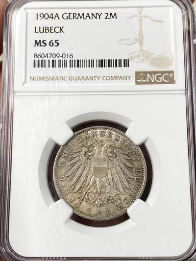 万国钱币拍卖第062期 - NGC MS65 1904年德国吕贝克自由市流通长翅2马克 原味淡金彩洒落在丝绸转光底板之上 顶级BU收藏品质