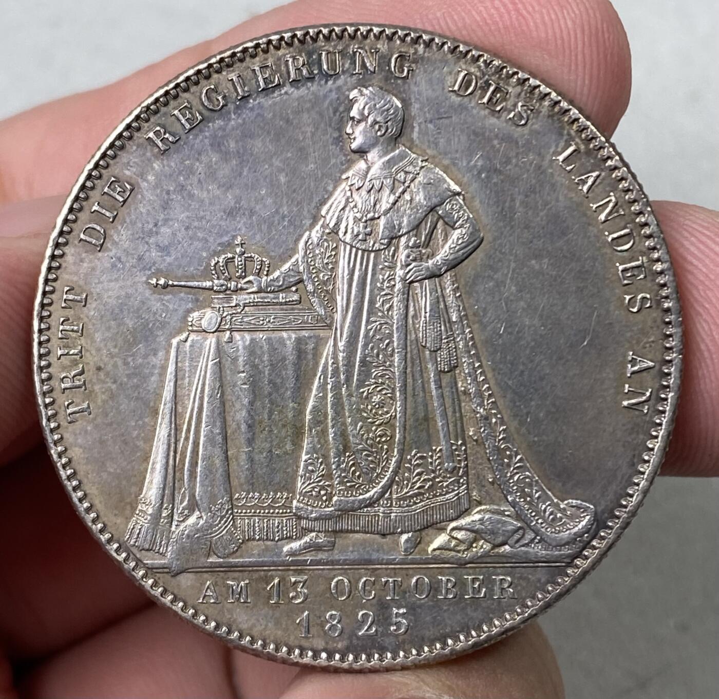 万国钱币拍卖第062期 1825年德国巴伐利亚路德维希一世加冕纪念历史大泰勒  历史泰勒系列开山之作 记录了国王路德维希一世登基加冕克承大统的重要时刻 路一身穿金丝镶边华服 颈戴十字架吊坠 左手握剑 右手持权杖 置于桌面的宪法之上 手边还有王冠一顶  德系历史泰勒名品