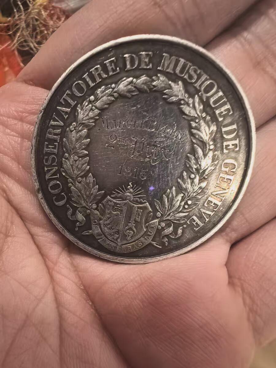 欧洲银章铜章、银币 日内瓦音乐学院银质纪念银章34.2克 这是一枚来自瑞士日内瓦音乐学院（Conservatoire de Musique de Genève）的银质纪念章，是为了表彰1915年的优秀学生Marcel Blouin而颁发的。 正面（Avers）二等奖