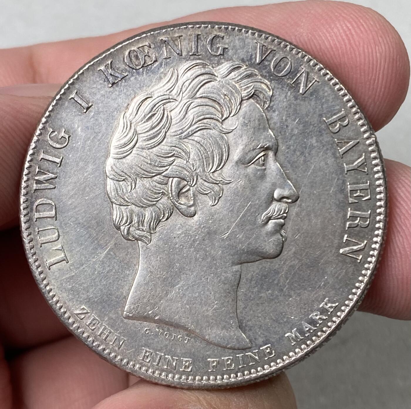 万国钱币拍卖第062期 1825年德国巴伐利亚路德维希一世加冕纪念历史大泰勒  历史泰勒系列开山之作 记录了国王路德维希一世登基加冕克承大统的重要时刻 路一身穿金丝镶边华服 颈戴十字架吊坠 左手握剑 右手持权杖 置于桌面的宪法之上 手边还有王冠一顶  德系历史泰勒名品