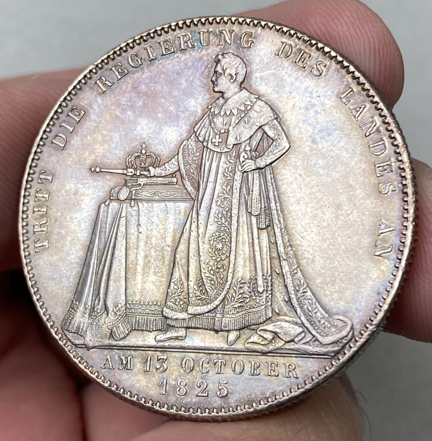 万国钱币拍卖第062期 1825年德国巴伐利亚路德维希一世加冕纪念历史大泰勒  历史泰勒系列开山之作 记录了国王路德维希一世登基加冕克承大统的重要时刻 路一身穿金丝镶边华服 颈戴十字架吊坠 左手握剑 右手持权杖 置于桌面的宪法之上 手边还有王冠一顶  德系历史泰勒名品