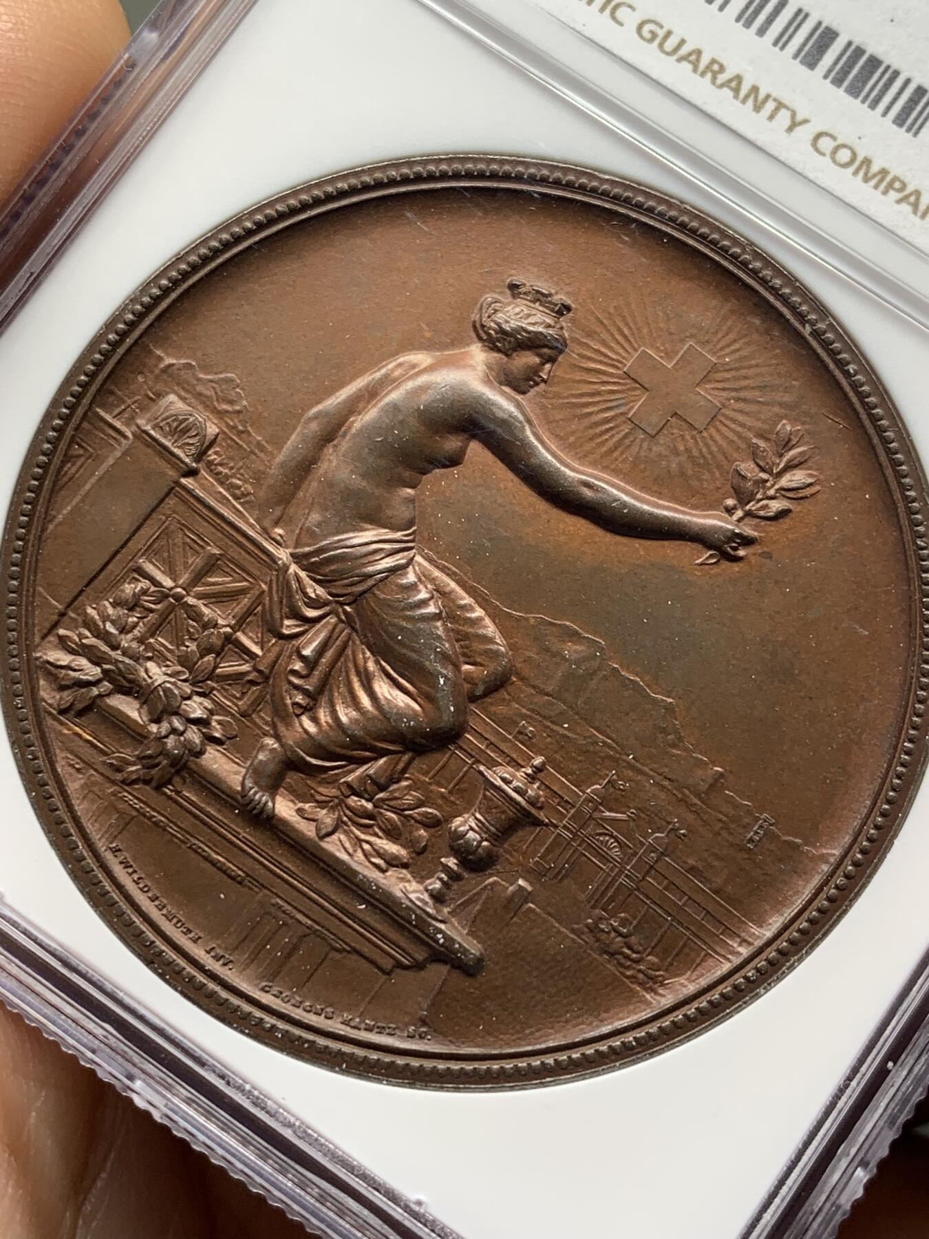 《竞宝斋》第471场 周日，周一，周二 3场连拍 （全场包邮）欢迎送拍 NGC MS64BN 瑞士1895年景观大铜章，正面女神捧花，背面市景和双人物头像，高浮雕设计，丝滑巧克力。