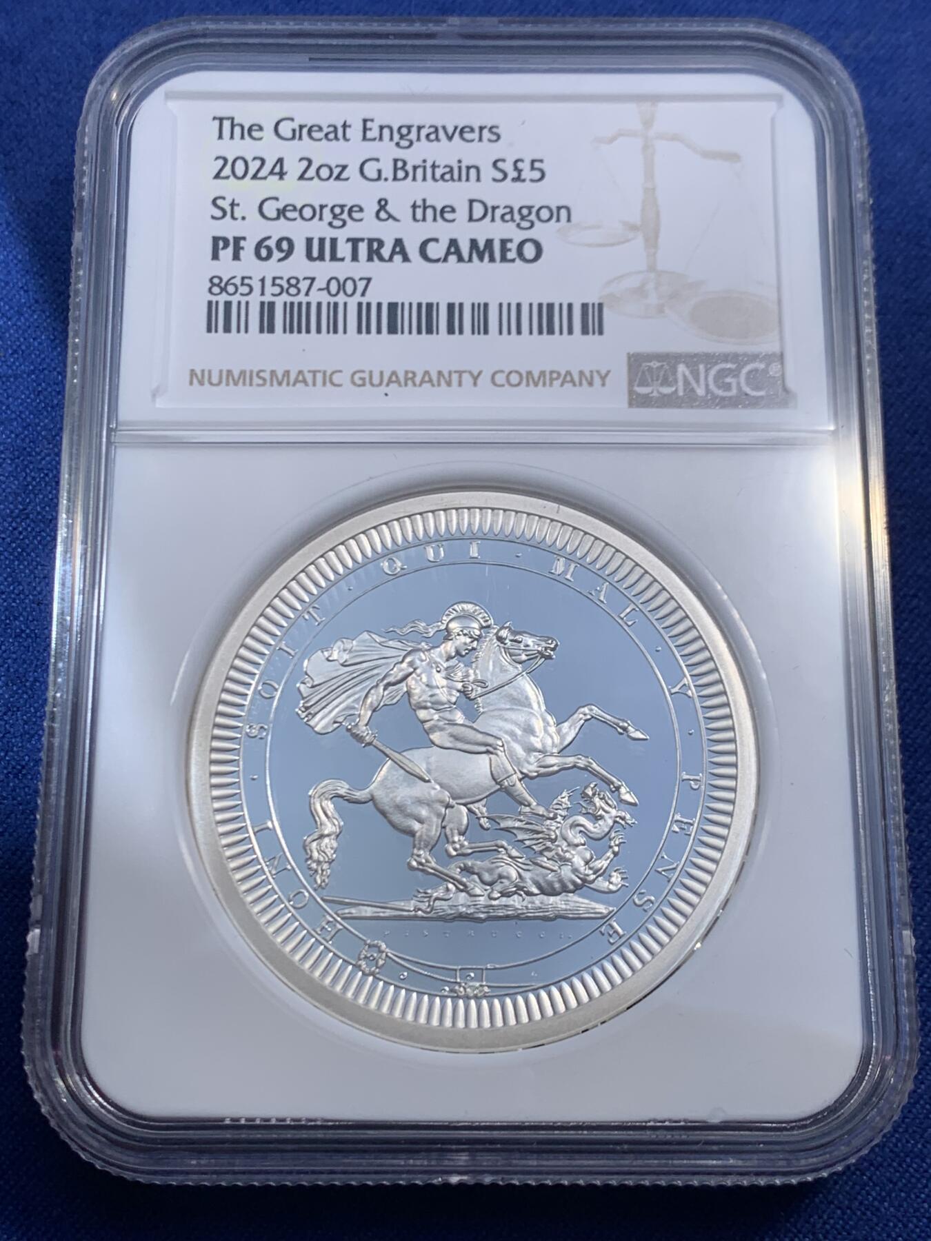 《竞宝斋》第471场 周日，周一，周二 3场连拍 （全场包邮）欢迎送拍 NGC PF69UC 英国2024年伟大的雕刻师系列-圣乔治屠龙纪念银币，2盎司，999银，面值5英镑。正面为著名雕刻大师皮斯特鲁奇设计的经典造型“圣乔治屠龙”，重量62.42克，直径40毫米，发行量近3060枚，加厚评级盒，手感极佳，附送平凡人保护壳！