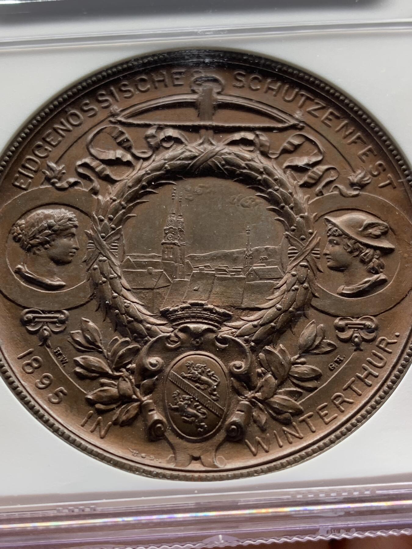 《竞宝斋》第471场 周日，周一，周二 3场连拍 （全场包邮）欢迎送拍 NGC MS64BN 瑞士1895年景观大铜章，正面女神捧花，背面市景和双人物头像，高浮雕设计，丝滑巧克力。