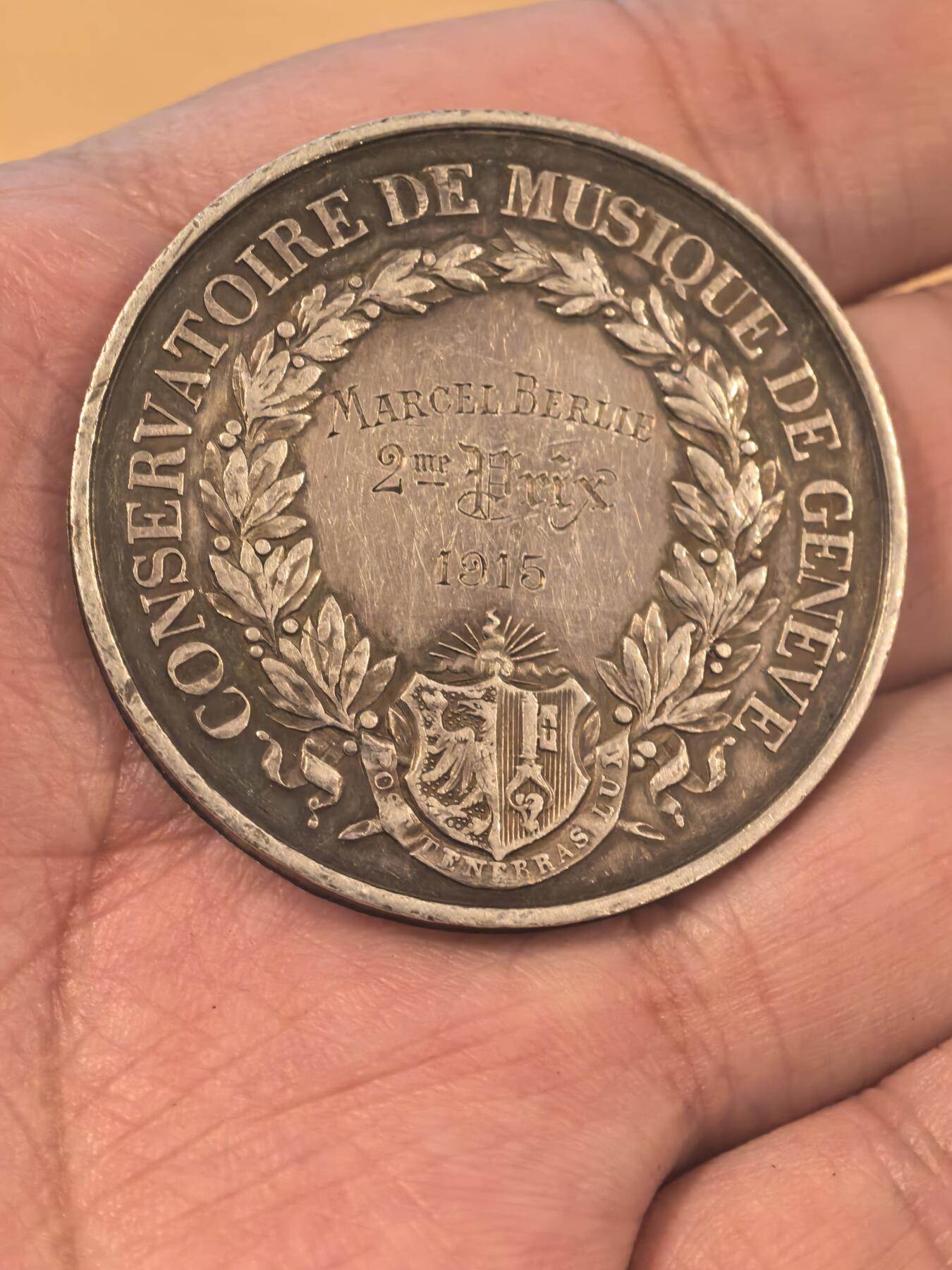 欧洲银章铜章、银币 日内瓦音乐学院银质纪念银章34.2克 这是一枚来自瑞士日内瓦音乐学院（Conservatoire de Musique de Genève）的银质纪念章，是为了表彰1915年的优秀学生Marcel Blouin而颁发的。 正面（Avers）二等奖