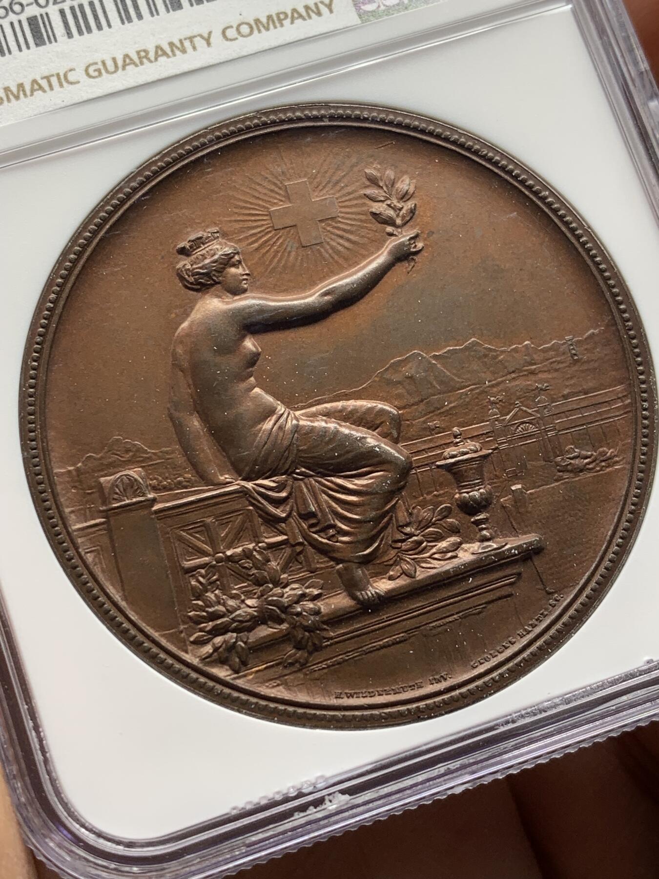 《竞宝斋》第471场 周日，周一，周二 3场连拍 （全场包邮）欢迎送拍 NGC MS64BN 瑞士1895年景观大铜章，正面女神捧花，背面市景和双人物头像，高浮雕设计，丝滑巧克力。