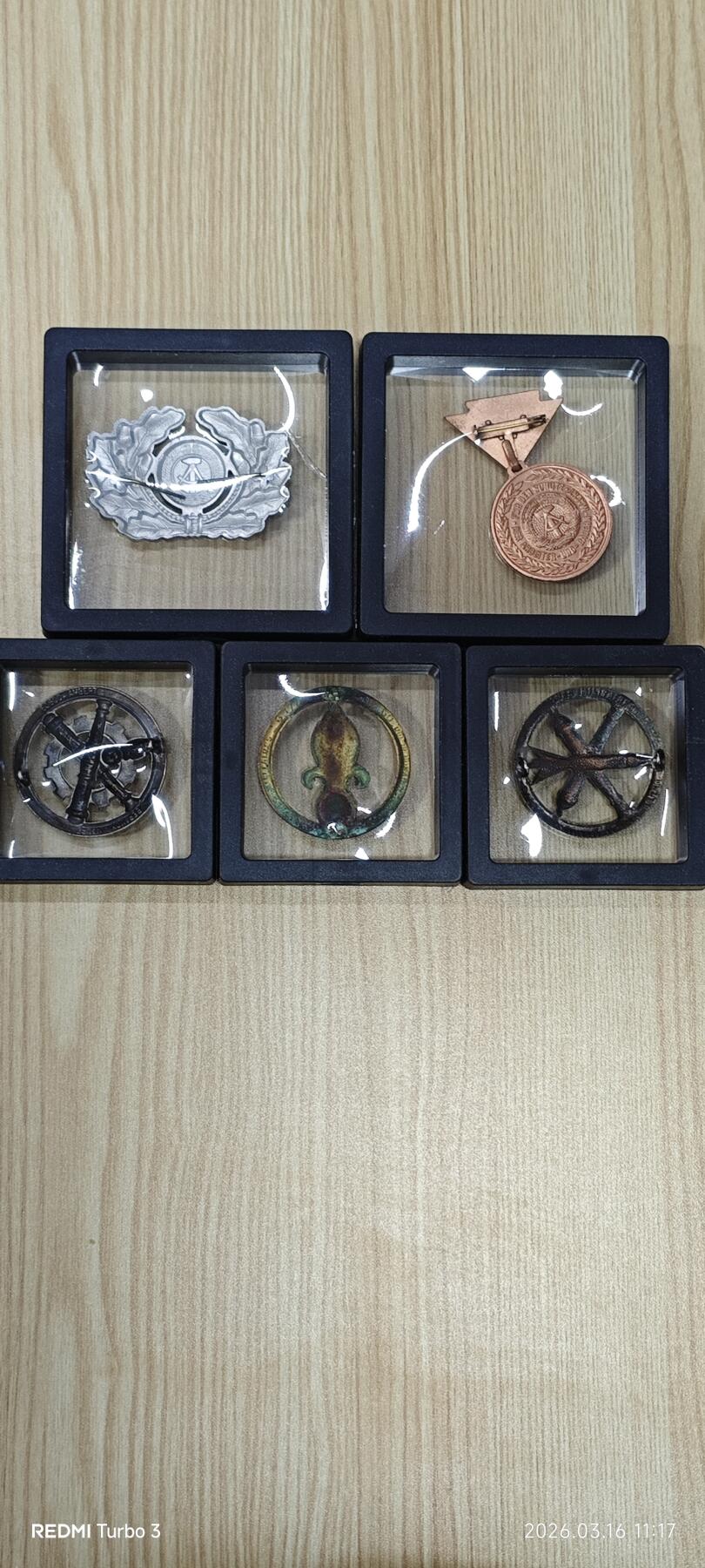 东德国家人民军（NVA）军官大檐帽徽、预备役铜质纪念章、工兵/炮兵兵种徽，搭配法国外籍军团鸢尾花贝雷帽徽，共5件。均为冷战时期原品，品相完好，细节清晰。适合军品收藏、历史研究或装饰展示。