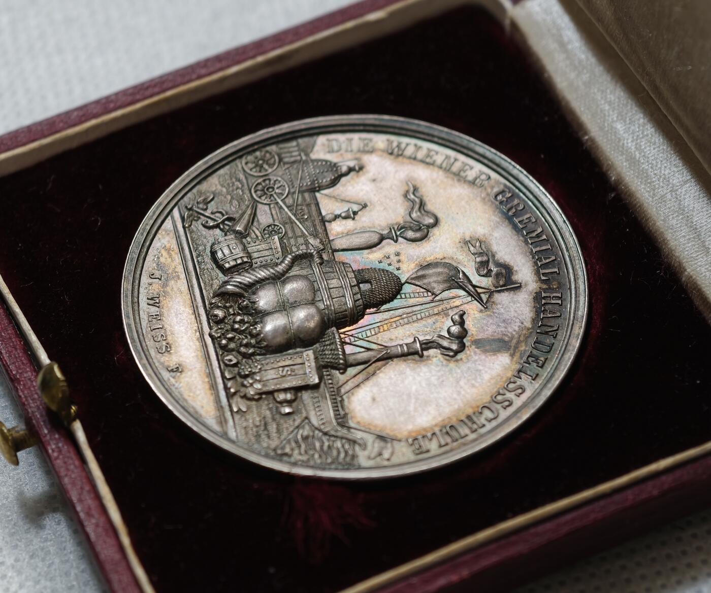 甄臻铺-世界币章拍卖（第55期），3月28日甄品场（直播拍卖）拍品征集中，送拍享返佣金等优惠多多 1891年奥地利维也纳商科学校颁发的银质奖章，直径43毫米，重21.9克，带原装皮盒。正面刻有“DIE WIENER GEMEINDE HANDELSCHULE”，背面“AUSGEZEICHNETEN SCHÜLER Hugo Winkler 1891”，环绕花环装饰，工艺精细，银质，包浆自然