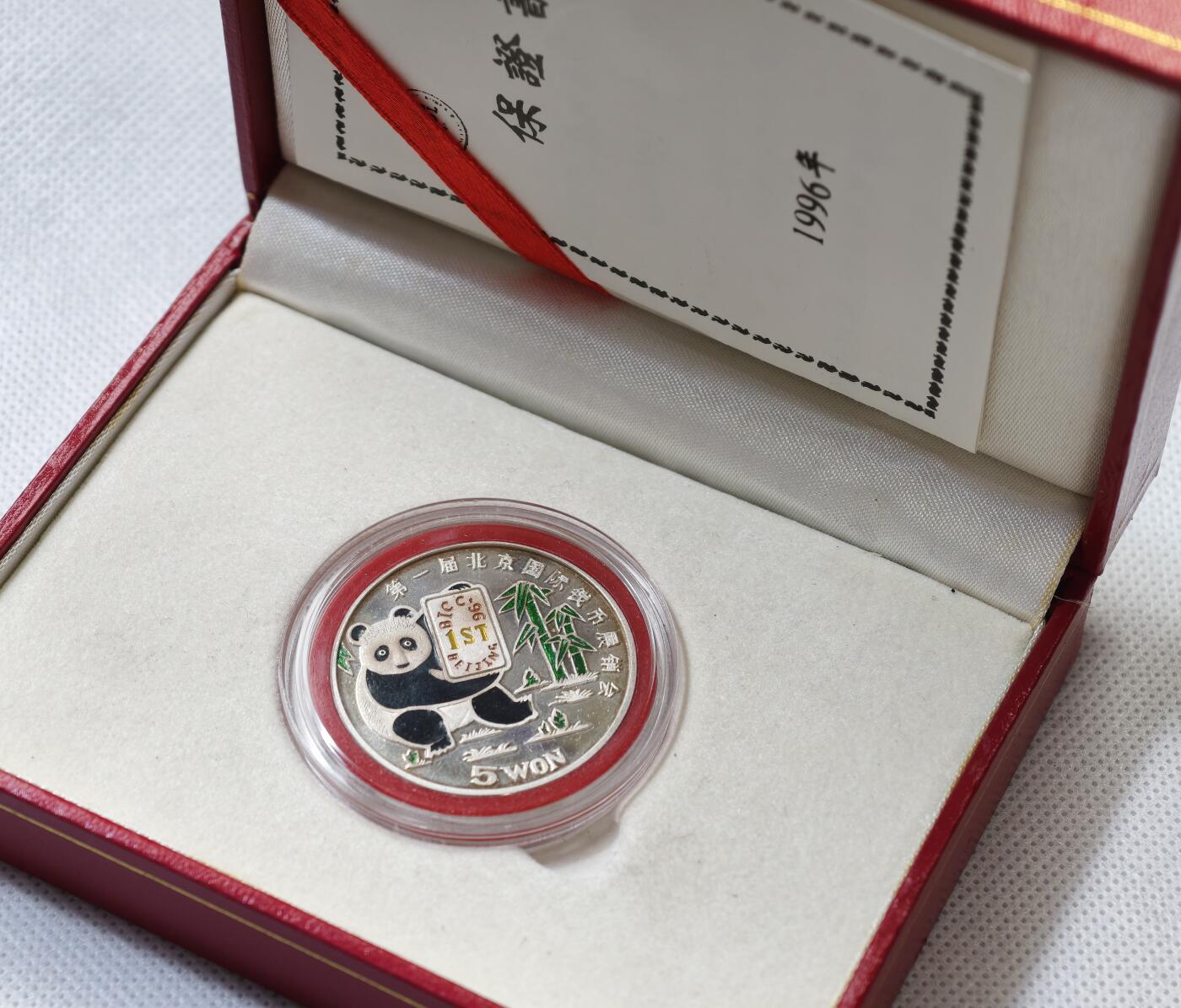 甄臻铺-世界币章拍卖（第55期），3月28日甄品场（直播拍卖）拍品征集中，送拍享返佣金等优惠多多 1996年朝鲜参加首届北京国际钱币展特别发行彩色熊猫币，仅发行6000枚，当年现场发售少部分，其余回流朝鲜，市场罕见，老精稀品种，盒证齐全