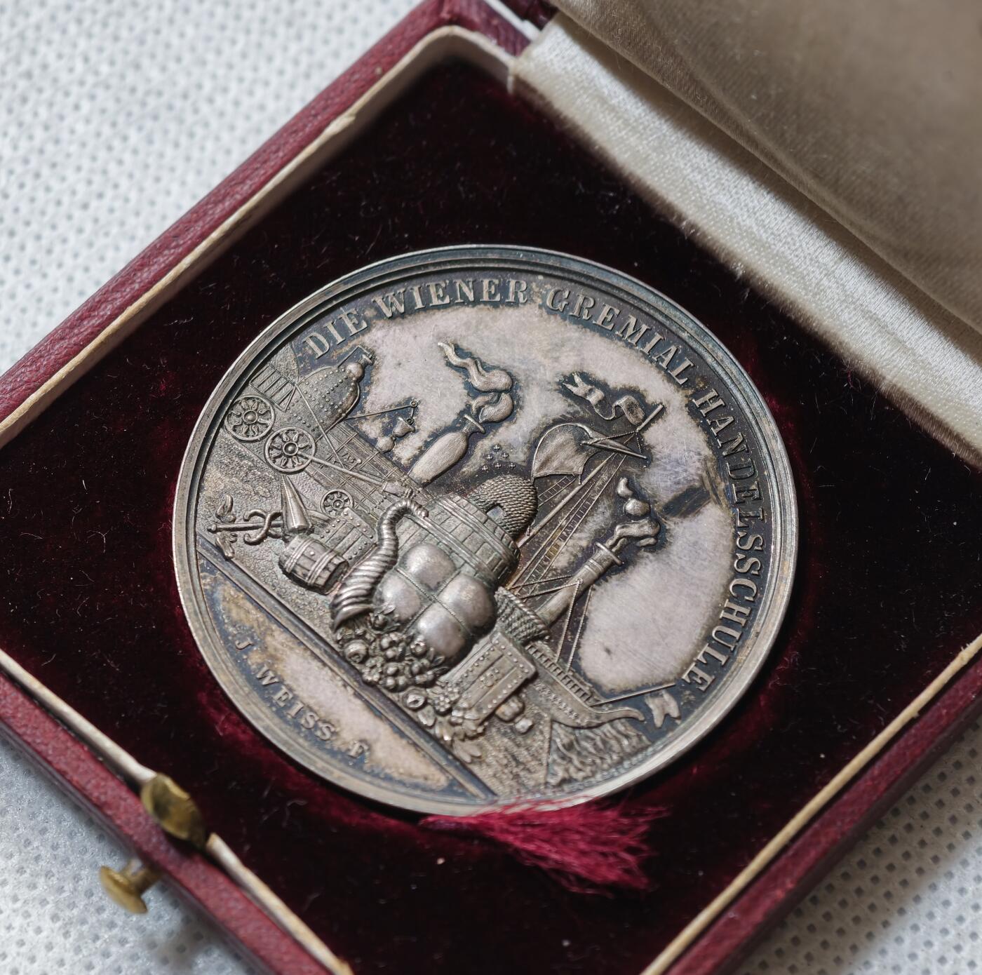 甄臻铺-世界币章拍卖（第55期），3月28日甄品场（直播拍卖）拍品征集中，送拍享返佣金等优惠多多 1891年奥地利维也纳商科学校颁发的银质奖章，直径43毫米，重21.9克，带原装皮盒。正面刻有“DIE WIENER GEMEINDE HANDELSCHULE”，背面“AUSGEZEICHNETEN SCHÜLER Hugo Winkler 1891”，环绕花环装饰，工艺精细，银质，包浆自然