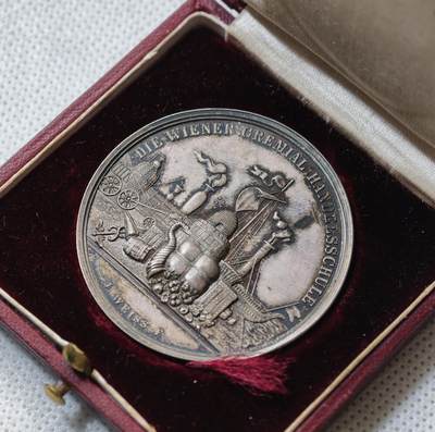 甄臻铺-世界币章拍卖（第55期），3月28日甄品场（直播拍卖）拍品征集中，送拍享返佣金等优惠多多 - 1891年奥地利维也纳商科学校颁发的银质奖章，直径43毫米，重21.9克，带原装皮盒。正面刻有“DIE WIENER GEMEINDE HANDELSCHULE”，背面“AUSGEZEICHNETEN SCHÜLER Hugo Winkler 1891”，环绕花环装饰，工艺精细，银质，包浆自然