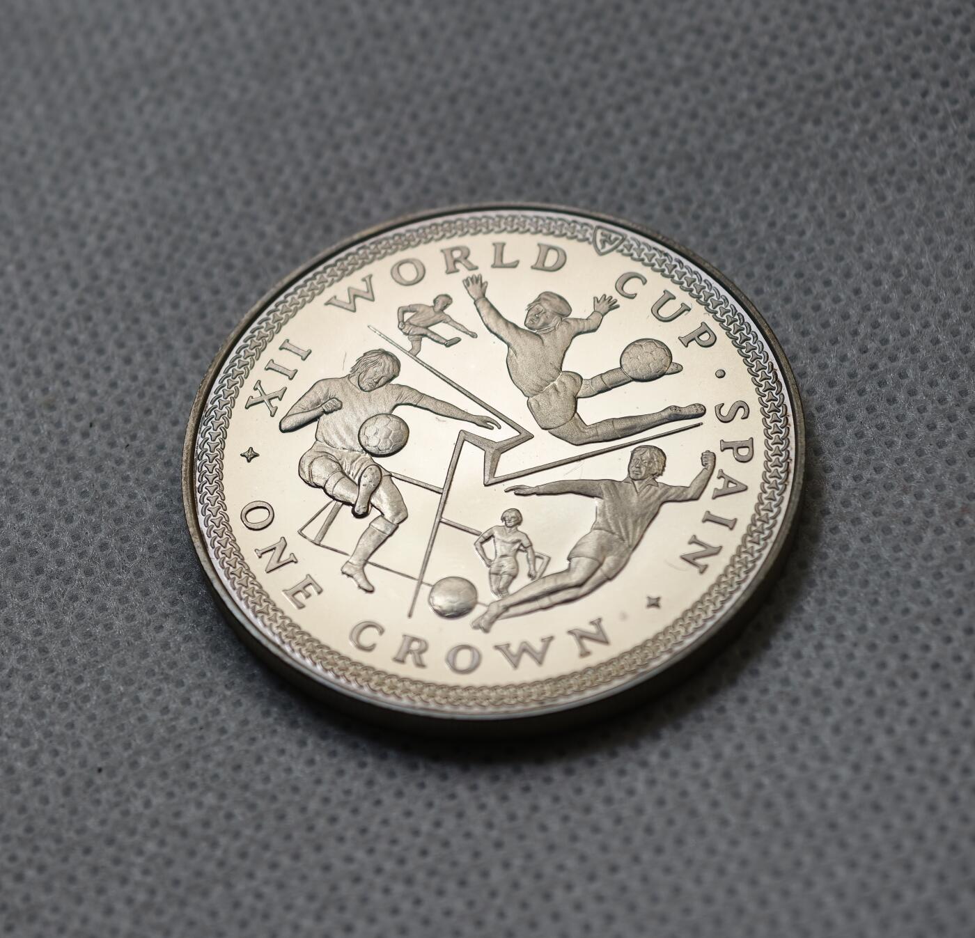 甄臻铺-世界币章拍卖（第55期），3月28日甄品场（直播拍卖）拍品征集中，送拍享返佣金等优惠多多 1982年马恩岛1克朗精制银币，FIFA世界杯主题，预热品种，发行量1.5万枚，28.5克925银