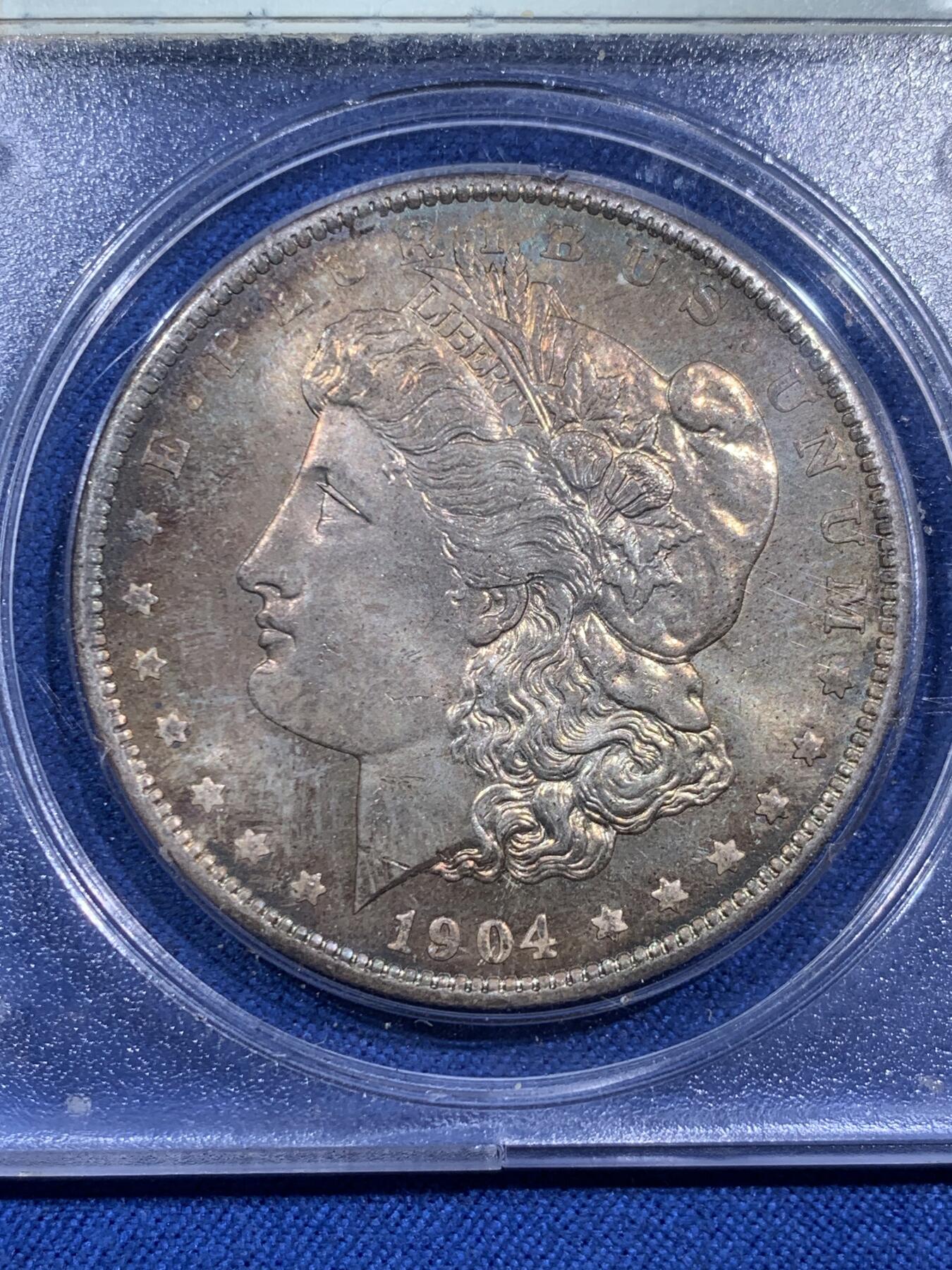 《竞宝斋》第473场 周日，周一 2场连拍 （全场包邮）欢迎送拍 PCGS MS64PL 美国1904-O 摩根1美元大银币，绝版初代P盒，盒子历史就已近40年。 PL大多是白币，彩币出PL极难，此枚绚丽五彩+PL镜面+绝版盒，真正藏家品质，摇摇乐不可多得的品种