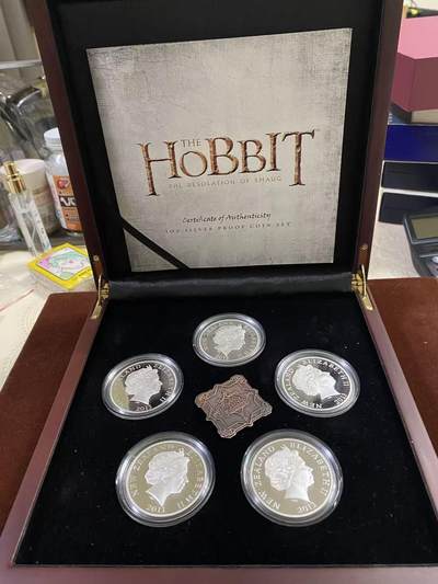 日日生财—方圆世界（全场包邮） - 2013年新西兰霍比特人电影系列银币套装，1盎司999银，精制工艺，面值$1，限量1000套。套装含5枚银币+1枚徽章，带原装木盒和证书