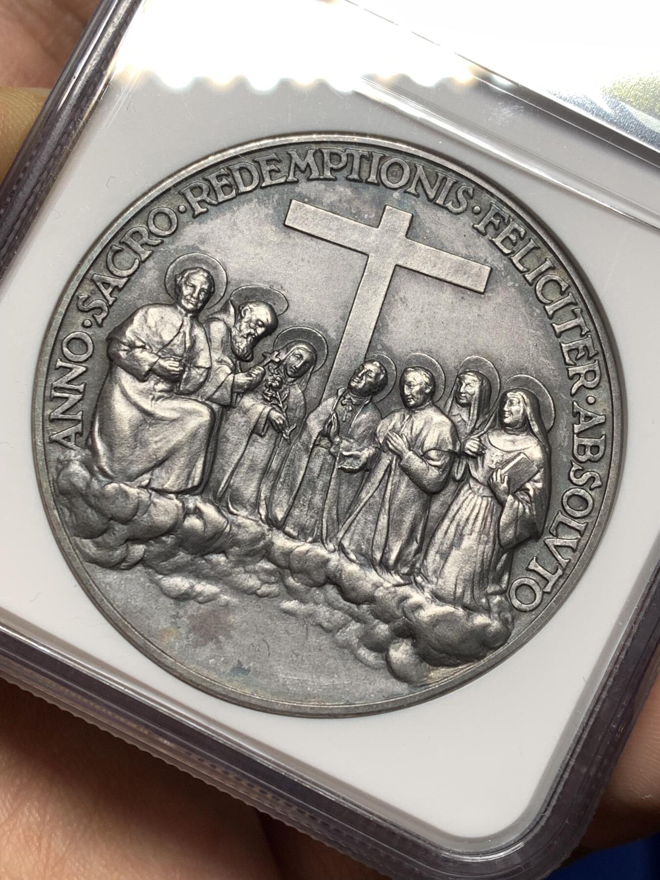 《竞宝斋》第474场 周日，周一 2场连拍 （全场包邮）欢迎送拍 NGC MS64 高分，加厚盒，稀少品种。梵蒂冈教皇庇护十一世于1934年发行的银质纪念章，由雕刻师A.Mistruzzi设计，用于纪念七位圣人的封圣仪式。纪念章正面为教皇左侧半身像，身着教宗礼服；背面描绘七位圣人立于云上，背景有十字架，铭文为拉丁语意“神圣救赎之年圆满结束”。该章发行了稀少，极具收藏价值。