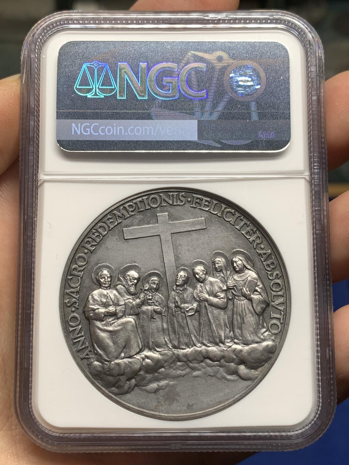 《竞宝斋》第474场 周日，周一 2场连拍 （全场包邮）欢迎送拍 NGC MS64 高分，加厚盒，稀少品种。梵蒂冈教皇庇护十一世于1934年发行的银质纪念章，由雕刻师A.Mistruzzi设计，用于纪念七位圣人的封圣仪式。纪念章正面为教皇左侧半身像，身着教宗礼服；背面描绘七位圣人立于云上，背景有十字架，铭文为拉丁语意“神圣救赎之年圆满结束”。该章发行了稀少，极具收藏价值。
