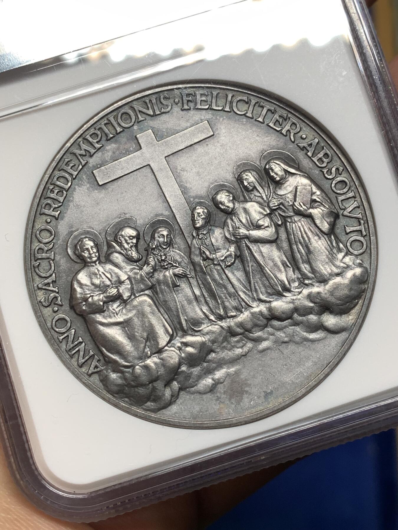 《竞宝斋》第474场 周日，周一 2场连拍 （全场包邮）欢迎送拍 NGC MS64 高分，加厚盒，稀少品种。梵蒂冈教皇庇护十一世于1934年发行的银质纪念章，由雕刻师A.Mistruzzi设计，用于纪念七位圣人的封圣仪式。纪念章正面为教皇左侧半身像，身着教宗礼服；背面描绘七位圣人立于云上，背景有十字架，铭文为拉丁语意“神圣救赎之年圆满结束”。该章发行了稀少，极具收藏价值。