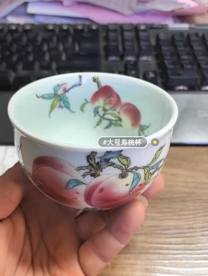 景德镇粉彩寿桃主人杯，全新未使用，纯手工绘制，画面精美，寓意福寿安康。底部有“景德镇珍藏”款识，陶瓷材质，手感细腻，收藏或日常品茶都很合适。  杯高约6厘米，口径约9厘米，容量约100毫升。