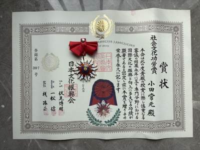 盛世勋华——号角文化勋章邮票专场拍卖第310期 - 日本文化振兴会社会文化功劳赏奖状与配套荣誉勋章，授予小田常元，登记号397号。奖状表彰其多年在专业领域为国际文化振兴与发展作出的卓越贡献，勋章为放射状菊花样式，红绶带，是民间文化荣誉的实物见证。大尺寸，厚重