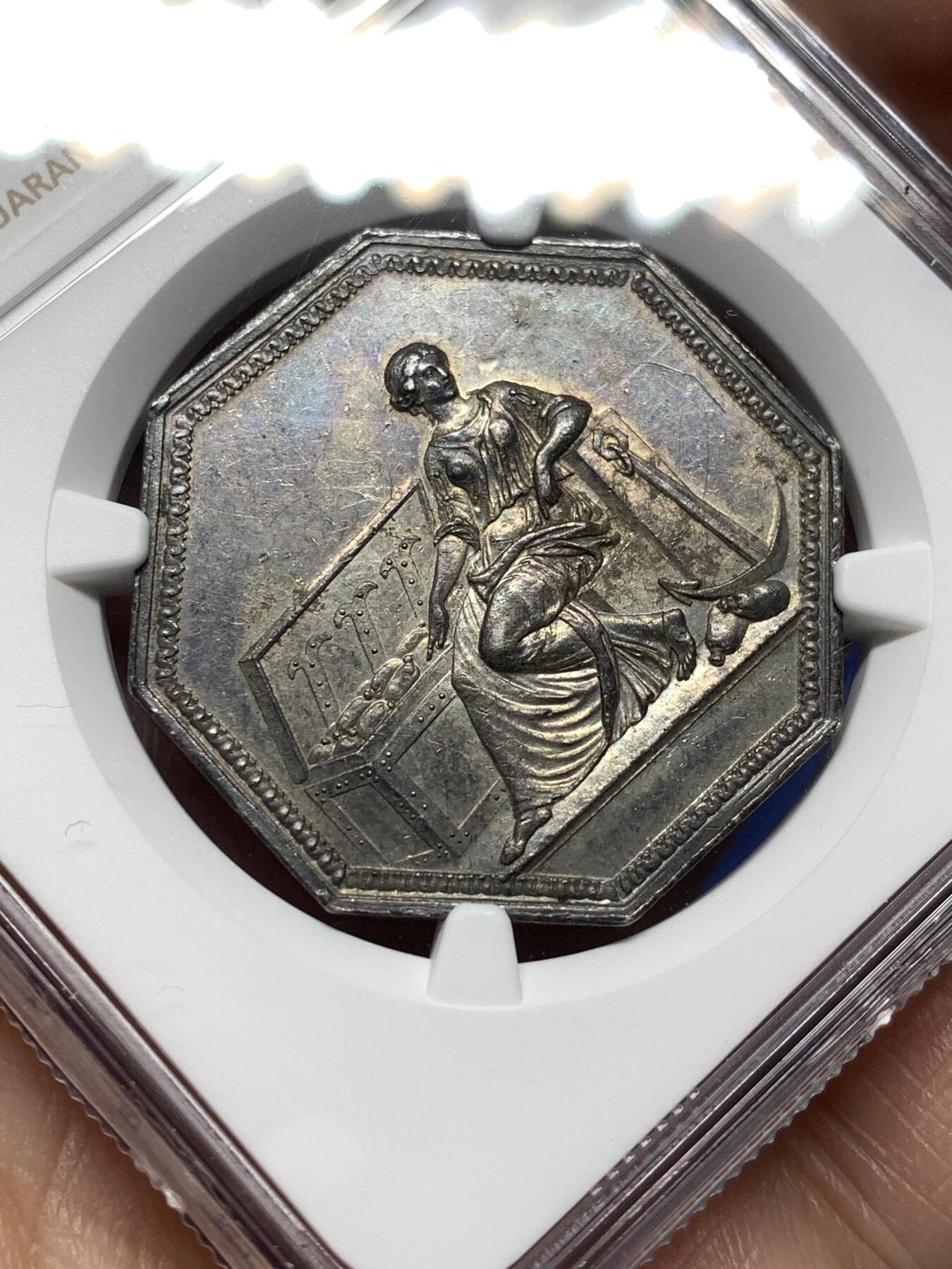 《竞宝斋》第474场 周日，周一 2场连拍 （全场包邮）欢迎送拍 NGC AU58 法国储蓄银行八角银质代币，早期无边铭，出分不易，少见款。正面：财富女神端坐，一旁的箱子里装满了财宝。