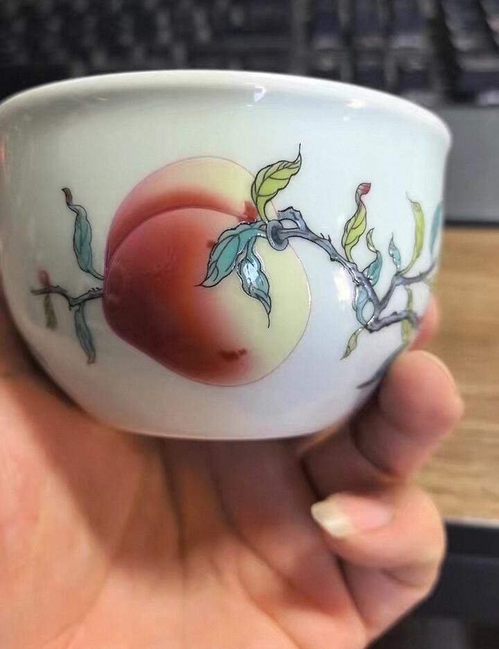 景德镇粉彩寿桃主人杯，全新未使用，纯手工绘制，画面精美，寓意福寿安康。底部有“景德镇珍藏”款识，陶瓷材质，手感细腻，收藏或日常品茶都很合适。  杯高约6厘米，口径约9厘米，容量约100毫升。