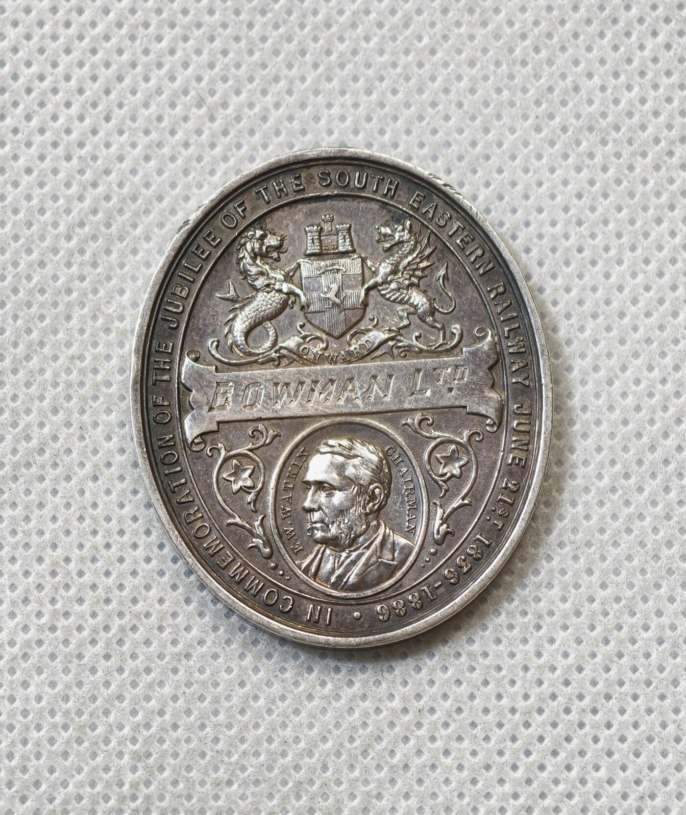 甄臻铺-世界币章拍卖（第56期），送拍享返佣金等优惠多多 1887年英国维多利亚女王登基50周年纪念获奖银章，由英国东南铁路公司颁发，椭圆形37.5x31.2毫米，重15克。正面维多利亚女王侧像，背面南东铁路徽章和人物肖像，见图，章顶部有貌似去吊环痕迹或许就是当时铸造时去浇口的痕迹，边缘有一处磕碰，其余完美。适合收藏或研究英国历史、铁路、维多利亚时期相关主题，非常稀少品种