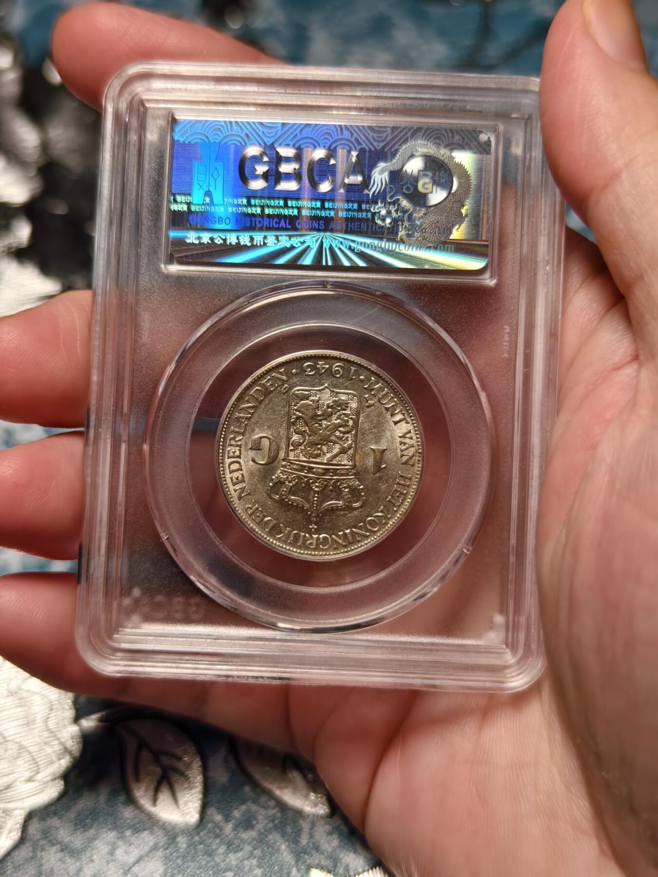 抚柳草堂-第十九期章牌钱币  奖章勋章限时免佣 满百包邮 放漏专场 1943荷属东印度1GULDEN银币 威廉敏娜女王 底板丝滑发丝清晰 公博ms63 二战期间荷兰本土被纳粹占领该币由美国丹佛造币厂铸造 主要供荷属东印度使用 是战时特殊发行的银币 