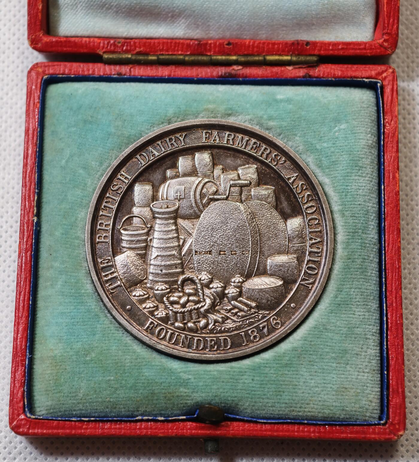 甄臻铺-世界币章拍卖（第56期），送拍享返佣金等优惠多多 1909年英国奶农协会（BRITISH DAIRY FARMERS ASSOCIATION）银质纪念章，直径47.5毫米，重43.722克，带原装红色皮盒。正面是奶牛和小牛图案，背面为奶制品和“FOUNDED 1876”字样，细节清晰，保存完好，包浆自然，带英国官方925银标。