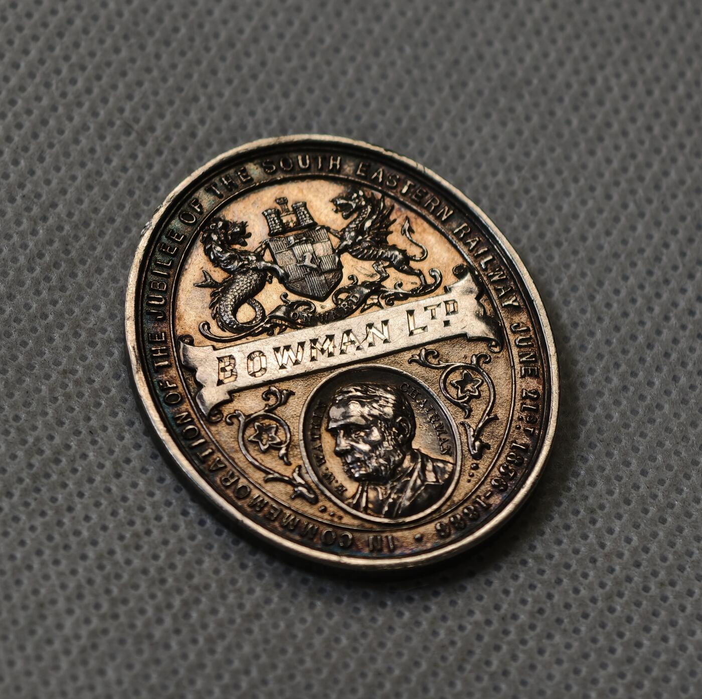 甄臻铺-世界币章拍卖（第56期），送拍享返佣金等优惠多多 1887年英国维多利亚女王登基50周年纪念获奖银章，由英国东南铁路公司颁发，椭圆形37.5x31.2毫米，重15克。正面维多利亚女王侧像，背面南东铁路徽章和人物肖像，见图，章顶部有貌似去吊环痕迹或许就是当时铸造时去浇口的痕迹，边缘有一处磕碰，其余完美。适合收藏或研究英国历史、铁路、维多利亚时期相关主题，非常稀少品种