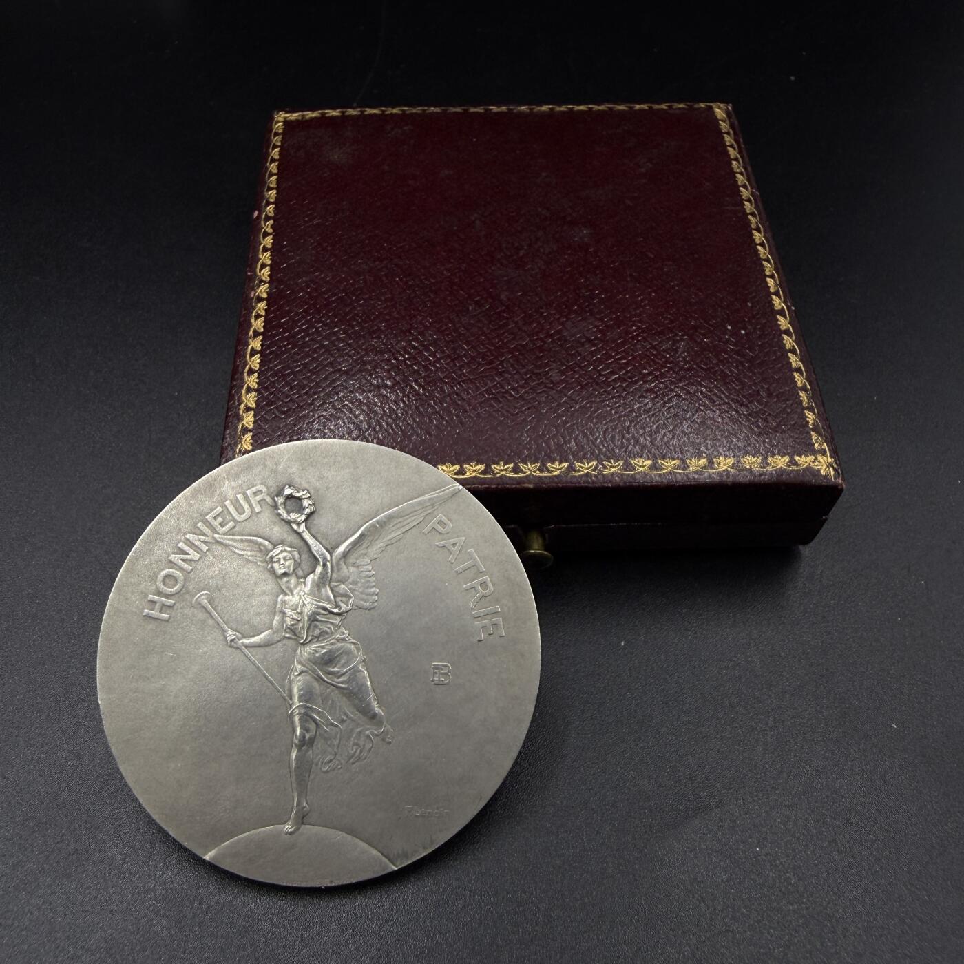 「木头集藏」“春启藏心”——章牌精品专场 P.Lenoir～法国射击协会联盟原盒银奖章，直径：44.5 mm，41.1 g，边铭：菱形厂标 野猪头银标 ARGENT，正面刻画胜利女神手持长号与月桂枝花环，向获奖人飞奔而来。品相不错，原盒正常使用。