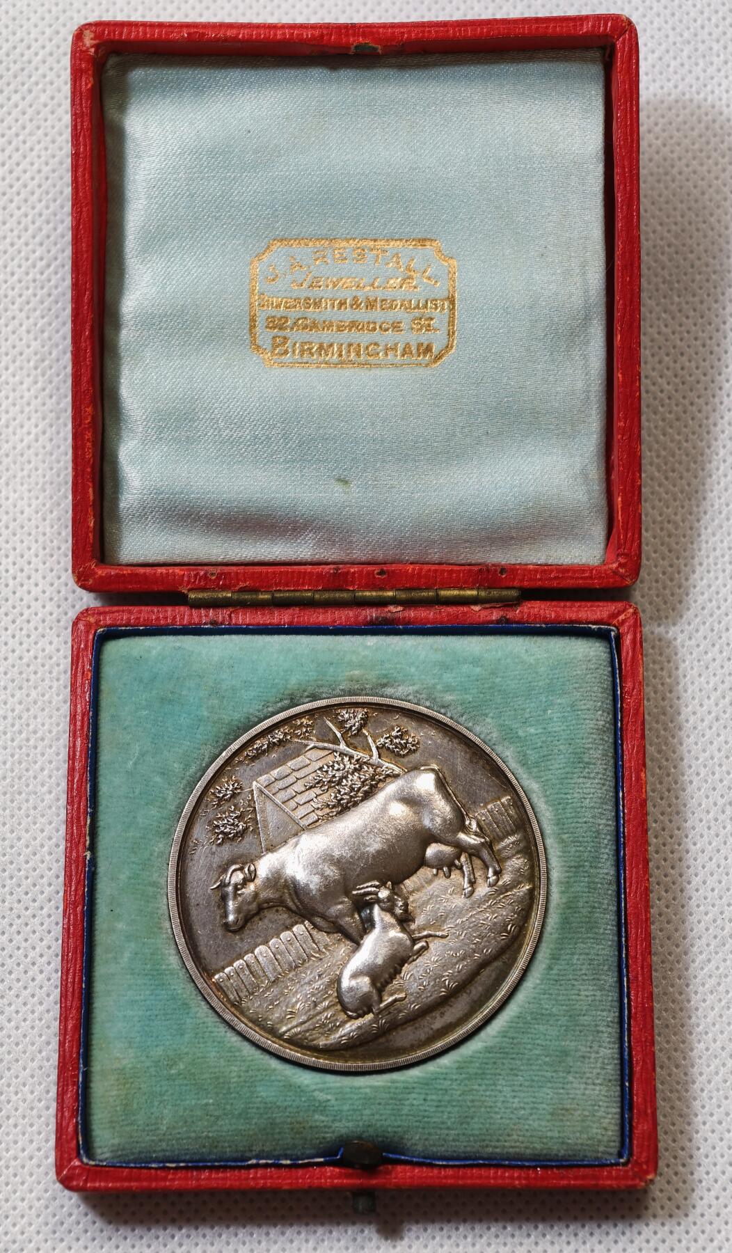 甄臻铺-世界币章拍卖（第56期），送拍享返佣金等优惠多多 1909年英国奶农协会（BRITISH DAIRY FARMERS ASSOCIATION）银质纪念章，直径47.5毫米，重43.722克，带原装红色皮盒。正面是奶牛和小牛图案，背面为奶制品和“FOUNDED 1876”字样，细节清晰，保存完好，包浆自然，带英国官方925银标。