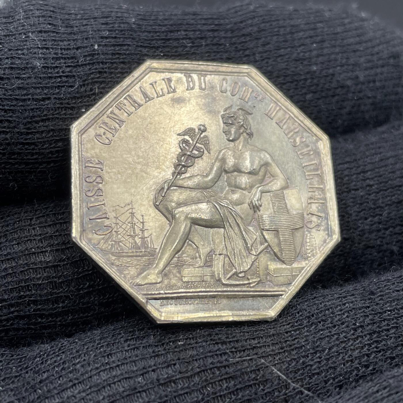 「木头集藏」“春启藏心”——章牌精品专场 1847年法国马赛商会中央金库八角银章，直径：30 mm，12.2 g，边铭：手指 ARGENT （1845-1860），少见八角。正面刻画商业之神赫尔墨斯的坐姿像，他手持双蛇杖（商业与贸易的象征），身旁有船锚、商船、盾牌（马赛市徽十字盾）与货箱，呼应马赛作为地中海商业港口的身份