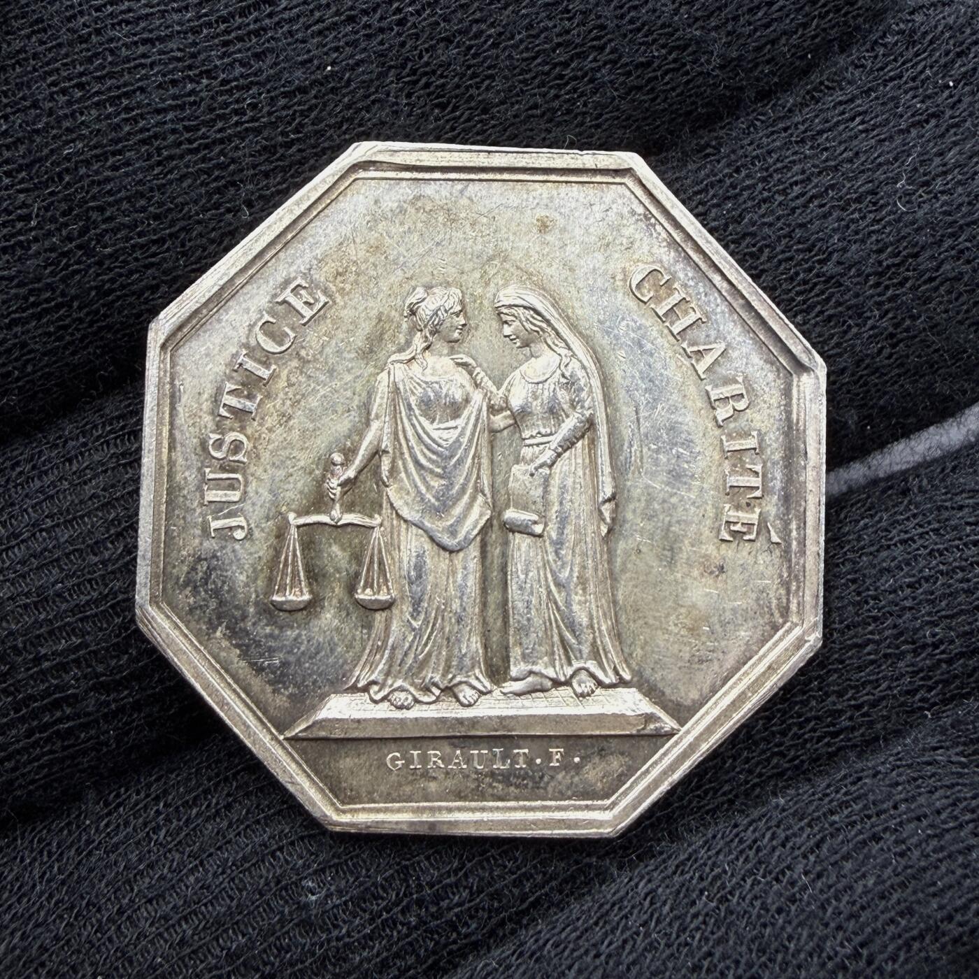 「木头集藏」“春启藏心”——章牌精品专场 Girault.F.～1843年法国马赛代诉人公会八角银章，直径：33.8 mm，12.5 g，边铭：船首 ARGENT （1842-1845年），正面刻画两位女神并肩而立，左侧为正义（JUSTICE），手持天平，代表法律的公平与公正；右侧为慈善（CHARITÉ），手持卷轴，象征司法中的人道与悲悯。二者相互依偎，体现了法国司法理念中“正义与慈悲并存”的核心精神。少见八角，初期版本，品相不错。