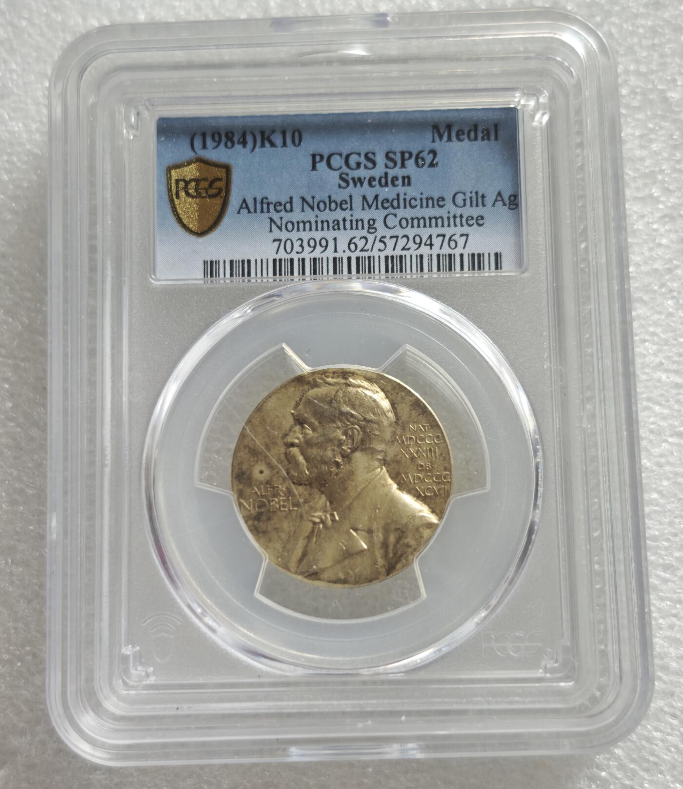瓶子🏺第234期拍卖会  瑞典诺贝尔医学奖提名委员会镀金银质纪念章（1984年）   这是一枚瑞典诺贝尔医学奖提名委员会发行的镀金银质纪念章，铸造于1984年，由PCGS评级为SP 62（样币级，未流通）阿斯克勒庇俄斯之杖（Rod of Asclepius），即蛇缠绕在权杖上，是医学的经典象征，下方搭配药碗与月桂叶（象征胜利与荣誉）这枚章是诺贝尔医学奖提名委员会的官方纪念章，用于表彰或馈赠参与诺贝尔医学奖提名的专家学者