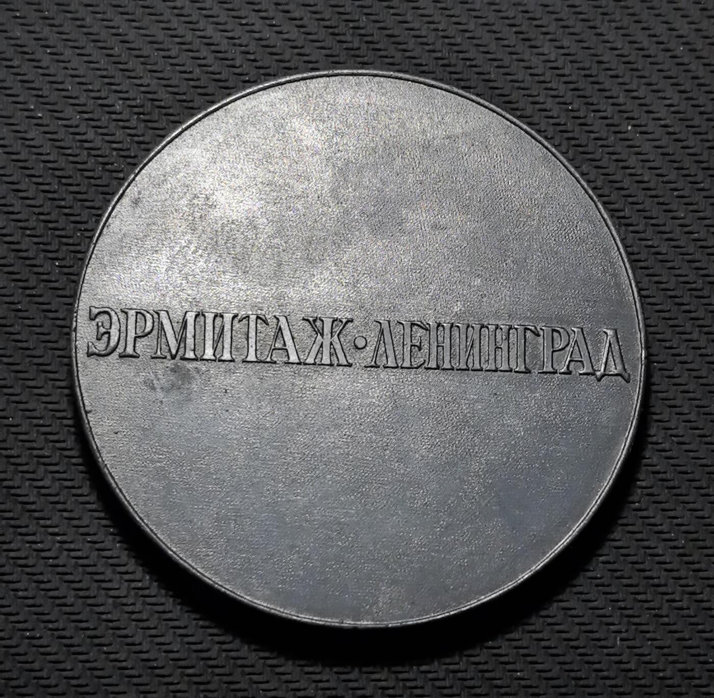 外国优质老铜币银币苏联纪念章，每周六晚九点倒数截拍，满百包邮可寄存，持续收拍 列宁格勒冬宫馆藏古希腊梳形文物纪念铜章直径70mm重99克，正面复刻古典武士搏杀浮雕与梳齿造型，还原古希腊艺术与生活器物的融合之美；背面标注 “ЭРМИТАЖ・ЛЕНИНГРАД”，彰显冬宫的文物典藏地位。铜质包浆冷峻厚重，古典浮雕细节硬核，是兼具西方艺术史与博物馆收藏价值的珍贵纪念章。
