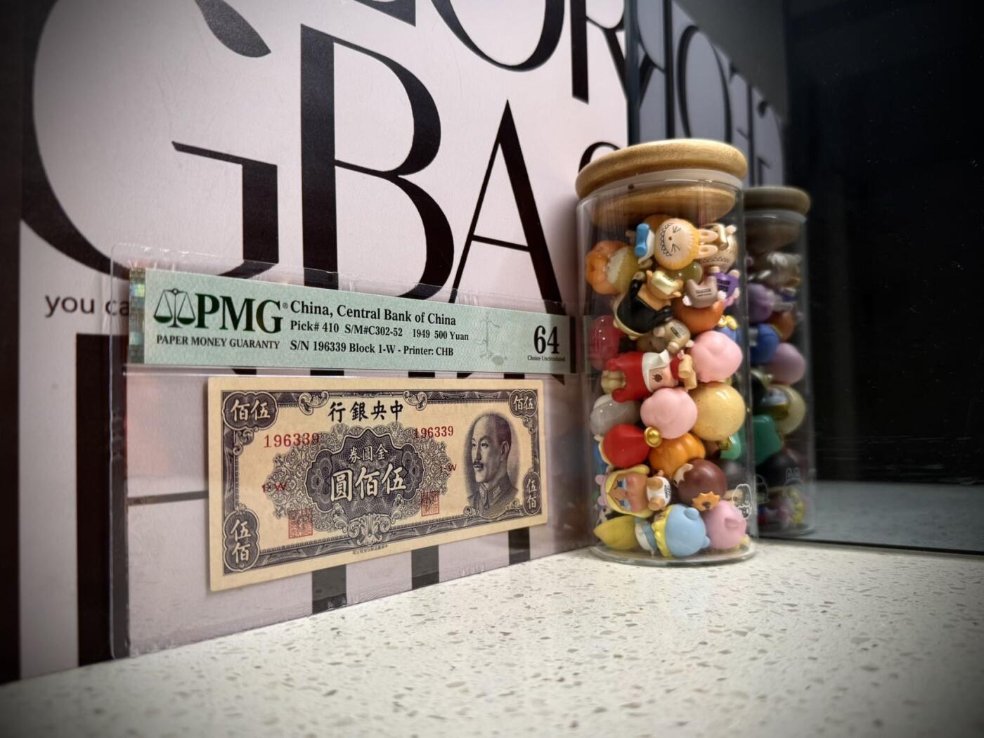 （自动截拍）PMG评级民国纸币专拍第20260330期，全场包邮 【乾奕收藏】出民国38年1949年中央银行中央厂金圆券伍佰圆，1963年3月9日生日号，号码全程无2457金山号靓号，多重题材，美国PMG64分