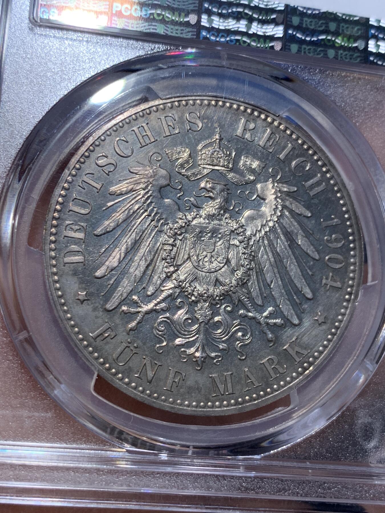 《竞宝斋》第475场 周日，周一 2场连拍 （全场包邮）欢迎送拍 PCGS PR64 德国1904年 梅克伦堡 什未林皇家大婚精制版纪念5马克，用以纪念弗里德里希·弗朗茨四世与汉诺威及坎伯兰的亚历山德拉公主的婚礼，发行量仅2500枚。币面呈现出耀眼的香槟色包浆，如水彩般铺展于表面，强烈的闪光照亮了镜面底板。无论在视觉效果上还是在技术品质上都堪称无可比拟，是极其令人向往的收藏佳品。