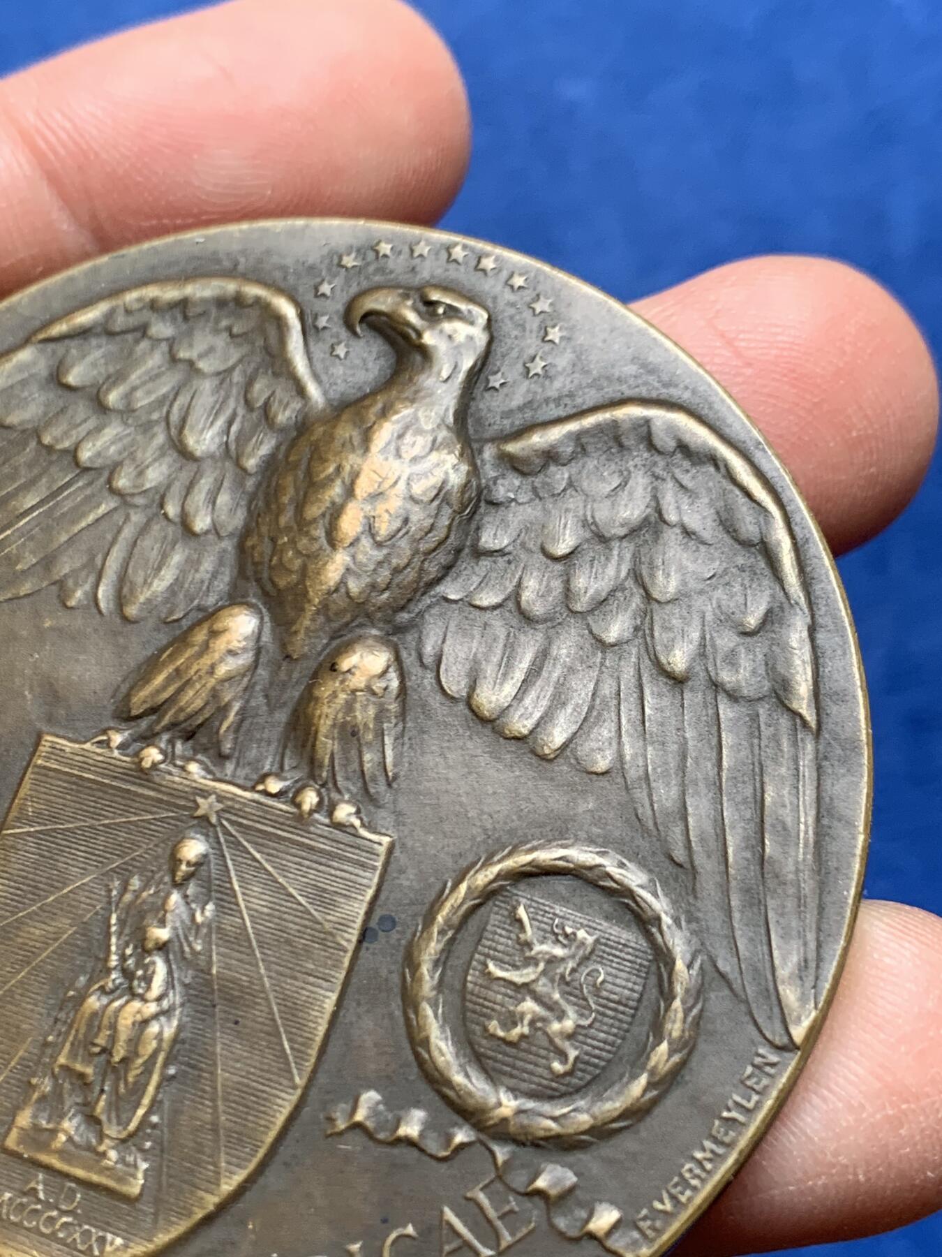 《竞宝斋》第475场 周日，周一 2场连拍 （全场包邮）欢迎送拍 1921年美国铸造比利时鲁汶大学图书馆纪念章，该纪念章英国帝国战争博物馆有藏，极具历史背景和意义，值得收藏品鉴，少见品。正面文字：（拉丁语，意为“美国于1921年恢复人道精神”）。图案：美国白头鹰立于盾徽之上，盾徽内是圣母与圣子像，两侧分别嵌有美国国旗纹章和比利时雄狮纹章，象征美比两国的联结。背面：（拉丁语，意为“1914年被德国军队焚毁的鲁汶大学图书馆”）。图案：刻画鲁汶大学图书馆内部的罗马式拱