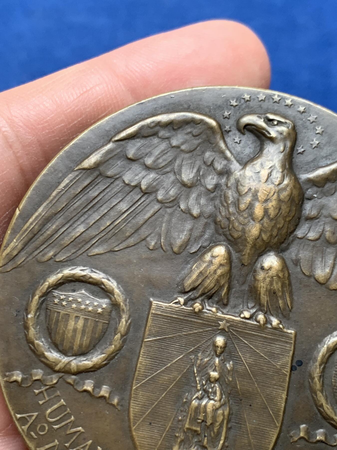 《竞宝斋》第475场 周日，周一 2场连拍 （全场包邮）欢迎送拍 1921年美国铸造比利时鲁汶大学图书馆纪念章，该纪念章英国帝国战争博物馆有藏，极具历史背景和意义，值得收藏品鉴，少见品。正面文字：（拉丁语，意为“美国于1921年恢复人道精神”）。图案：美国白头鹰立于盾徽之上，盾徽内是圣母与圣子像，两侧分别嵌有美国国旗纹章和比利时雄狮纹章，象征美比两国的联结。背面：（拉丁语，意为“1914年被德国军队焚毁的鲁汶大学图书馆”）。图案：刻画鲁汶大学图书馆内部的罗马式拱