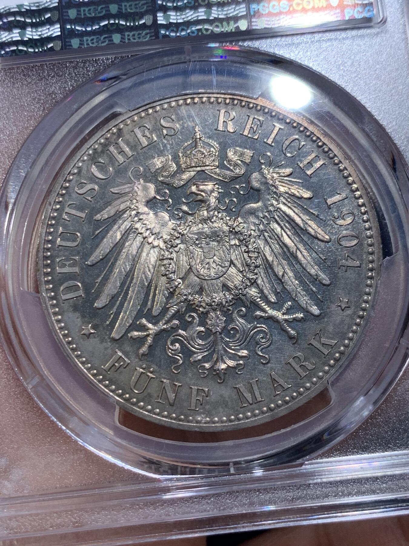 《竞宝斋》第475场 周日，周一 2场连拍 （全场包邮）欢迎送拍 PCGS PR64 德国1904年 梅克伦堡 什未林皇家大婚精制版纪念5马克，用以纪念弗里德里希·弗朗茨四世与汉诺威及坎伯兰的亚历山德拉公主的婚礼，发行量仅2500枚。币面呈现出耀眼的香槟色包浆，如水彩般铺展于表面，强烈的闪光照亮了镜面底板。无论在视觉效果上还是在技术品质上都堪称无可比拟，是极其令人向往的收藏佳品。