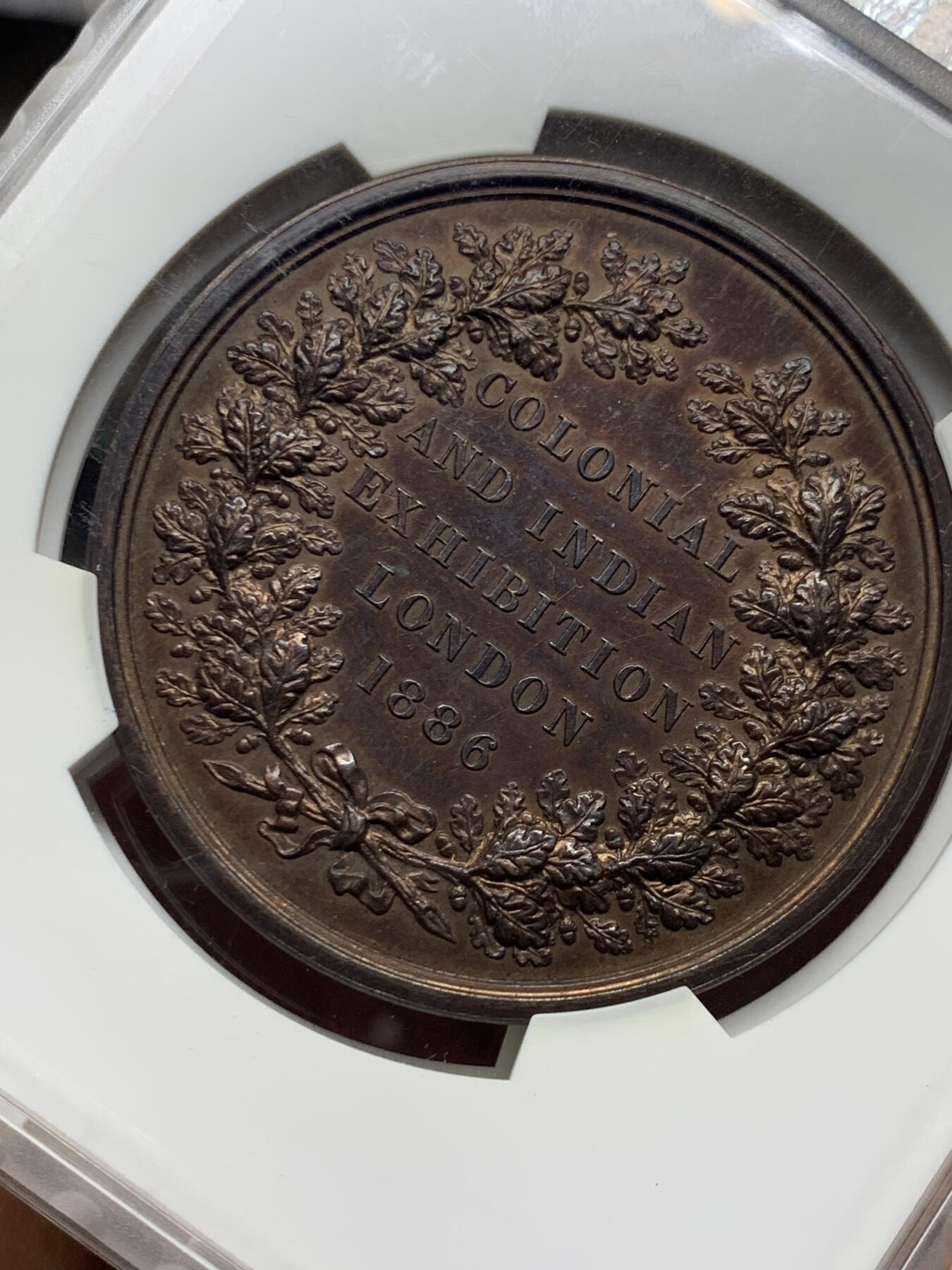 《竞宝斋》第476场 周日，周一 2场连拍 （全场包邮）欢迎送拍 1886年英国印度殖民地伦敦博览会纪念章，正面：此时尚未成为英国国王的威尔士亲王爱德华，背面：铭文纪念。皇家造币厂首席雕刻师L.C怀恩作品，直径约52毫米，重约79克。少见品种！加大加厚盒