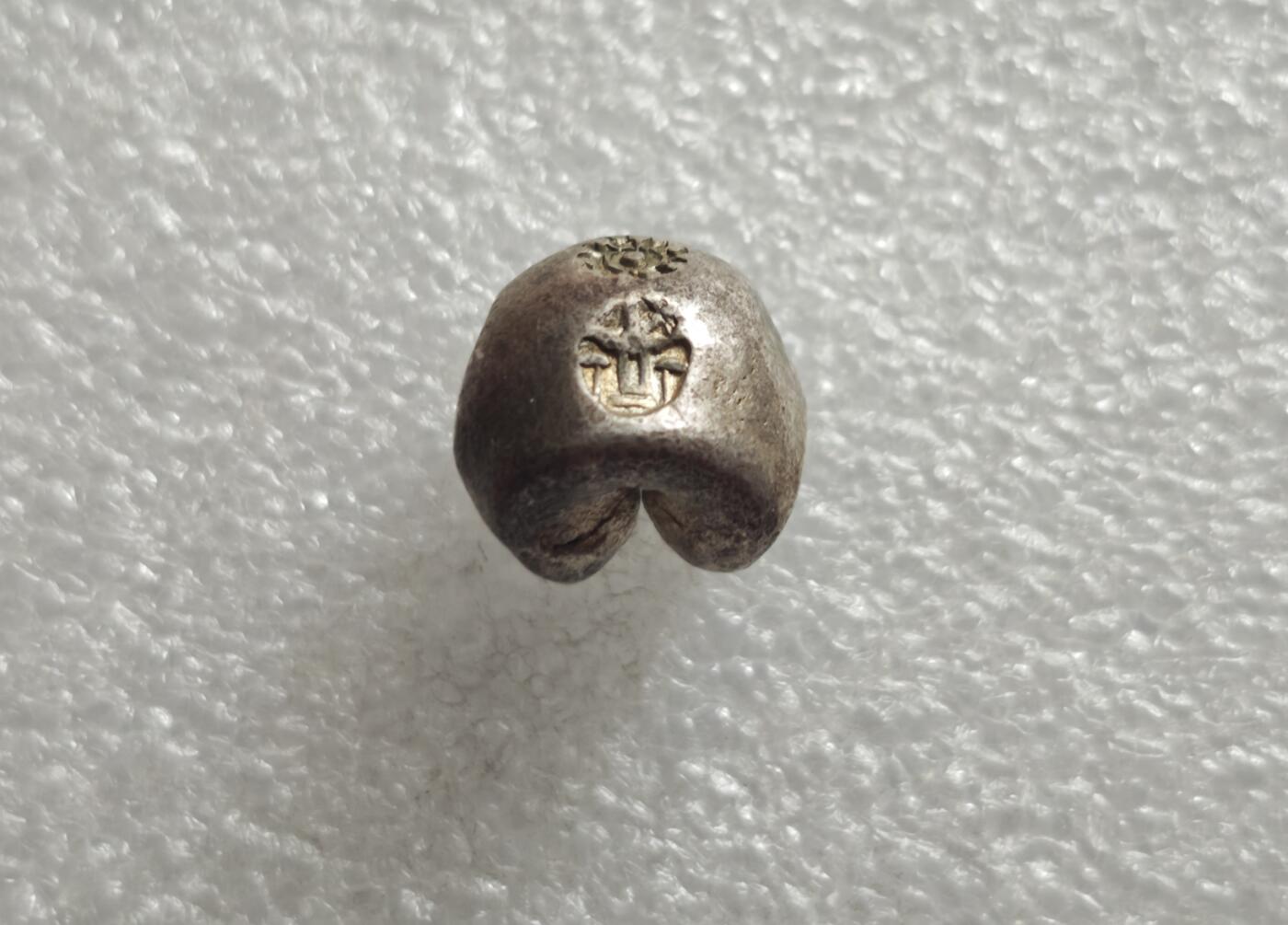 瓶子🏺第235期拍卖会  好品银光1泰铢（15克）  暹罗（泰国）拉玛王朝“屁股银”（Pod Duang / 子弹银）   泰国拉玛王朝（1782–1910年）时期流通的手工打制银锭，在闽南民间被形象称为“尻川银”（屁股银），西方则称其为“子弹银”（Bullet Money） 上方轮形戳记代表法轮，是暹罗王室与佛教法统的象征，寓意佛法永转、王权正统 ​  下方戳记对应拉玛王朝君主的皇家徽记 拉玛四世的“Mongkut”徽