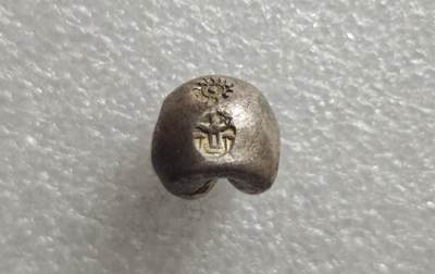 瓶子🏺第235期拍卖会 -  好品银光1泰铢（15.08克）  暹罗拉玛王朝“屁股银”（Pod Duang / 子弹银）   泰国拉玛王朝（1782–1910年）时期流通的手工打制银锭，在闽南民间被形象称为“尻川银”（屁股银），西方则称其为“子弹银”（Bullet Money） 上方轮形戳记代表法轮，是暹罗王室与佛教法统的象征，寓意佛法永转、王权正统 ​  下方戳记对应拉玛王朝君主的皇家徽记 拉玛四世的“Mongkut”徽