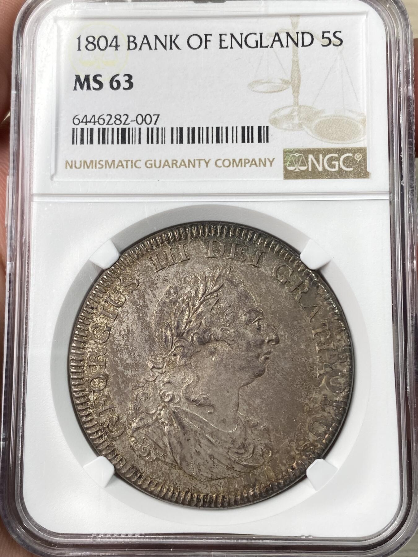 万国钱币拍卖第064期 NGC MS63 1804年英国乔治三世英格兰银行5先令大银 英国白银短缺时期的产物 直接压印在西班牙双柱之上 流通非常充分从而高品难得一见 此枚双柱币坯痕迹清晰可见 双面均匀一色的纸袋包浆极其原味 不可多得的典藏级品质 
