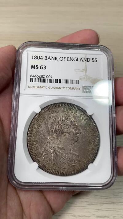 万国钱币拍卖第064期 NGC MS63 1804年英国乔治三世英格兰银行5先令大银 英国白银短缺时期的产物 直接压印在西班牙双柱之上 流通非常充分从而高品难得一见 此枚双柱币坯痕迹清晰可见 双面均匀一色的纸袋包浆极其原味 不可多得的典藏级品质 
