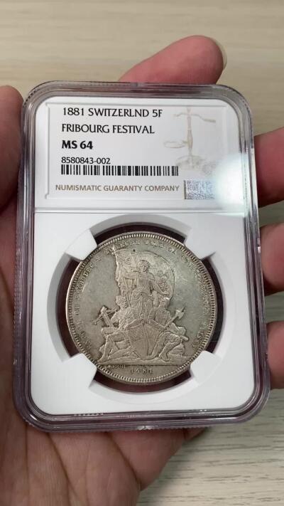 万国钱币拍卖第064期 NGC MS64 1881年瑞士弗里堡射击节经典城市景观5法郎 广受欢迎的瑞射景观系列 银霜转光香槟金淡彩环绕 极其舒适的收藏级品质