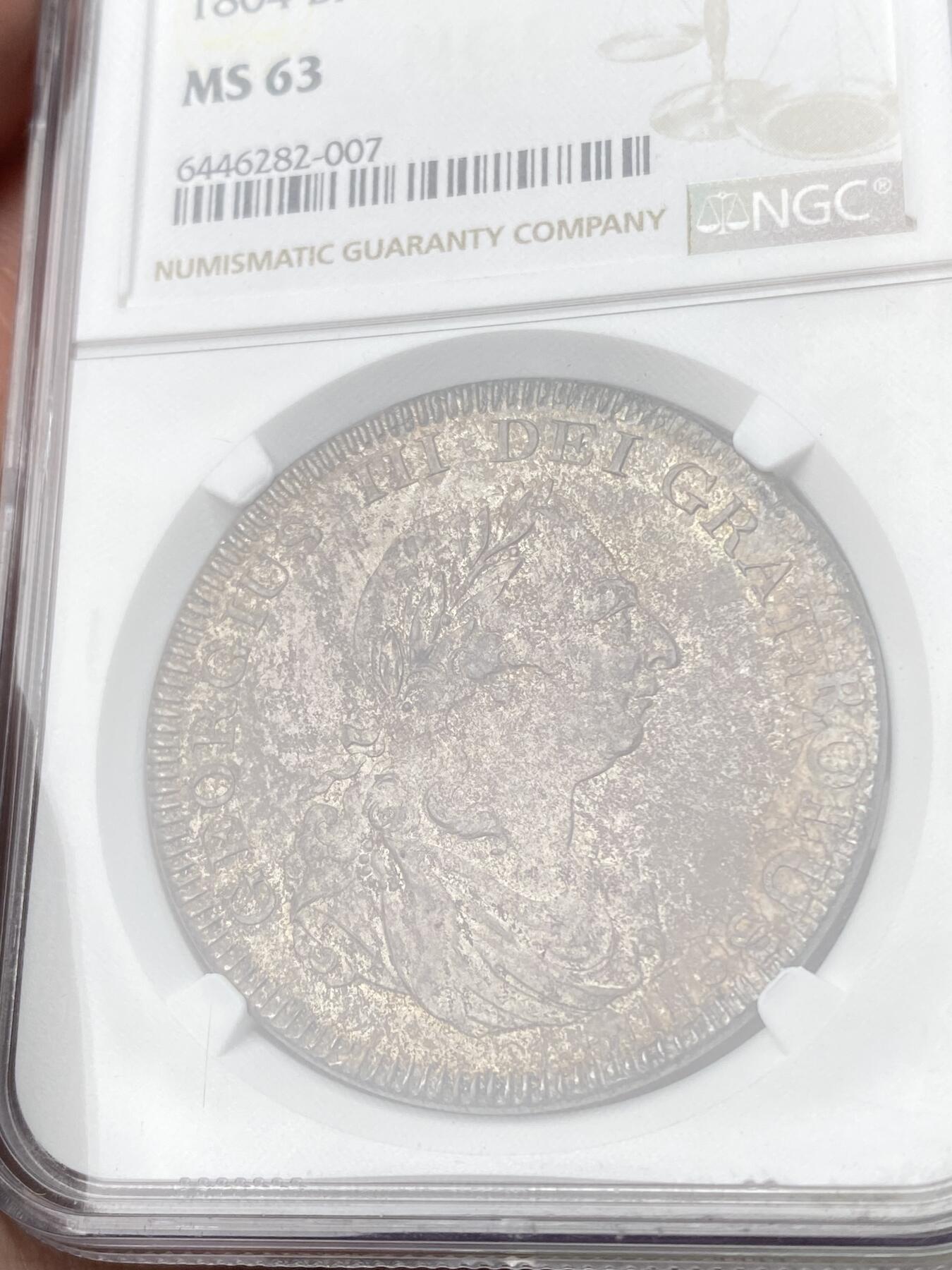 万国钱币拍卖第064期 NGC MS63 1804年英国乔治三世英格兰银行5先令大银 英国白银短缺时期的产物 直接压印在西班牙双柱之上 流通非常充分从而高品难得一见 此枚双柱币坯痕迹清晰可见 双面均匀一色的纸袋包浆极其原味 不可多得的典藏级品质 